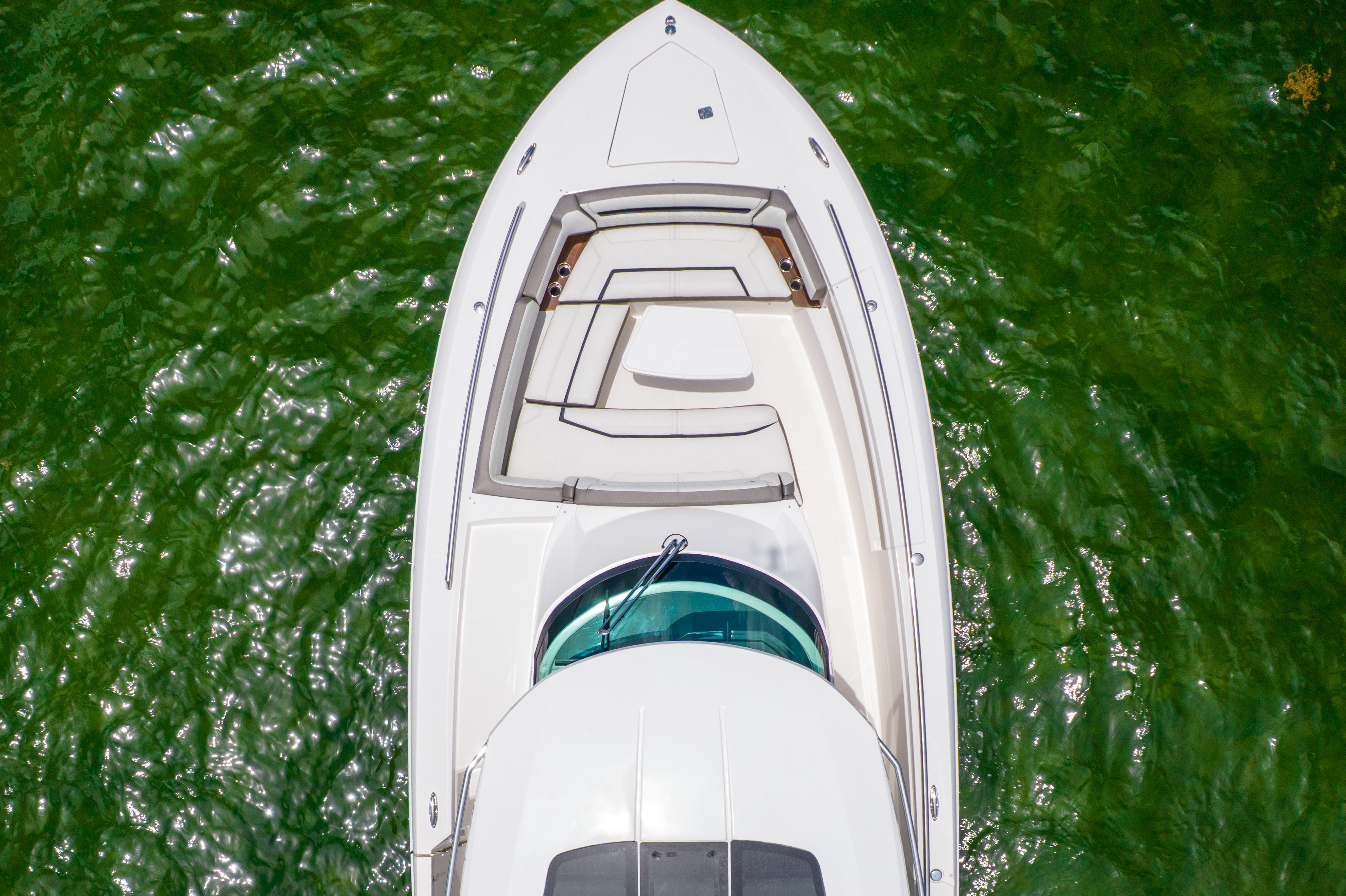 Aerial view of a 2023 Tiara Yachts 38 LS on green water, featuring sleek seating areas.