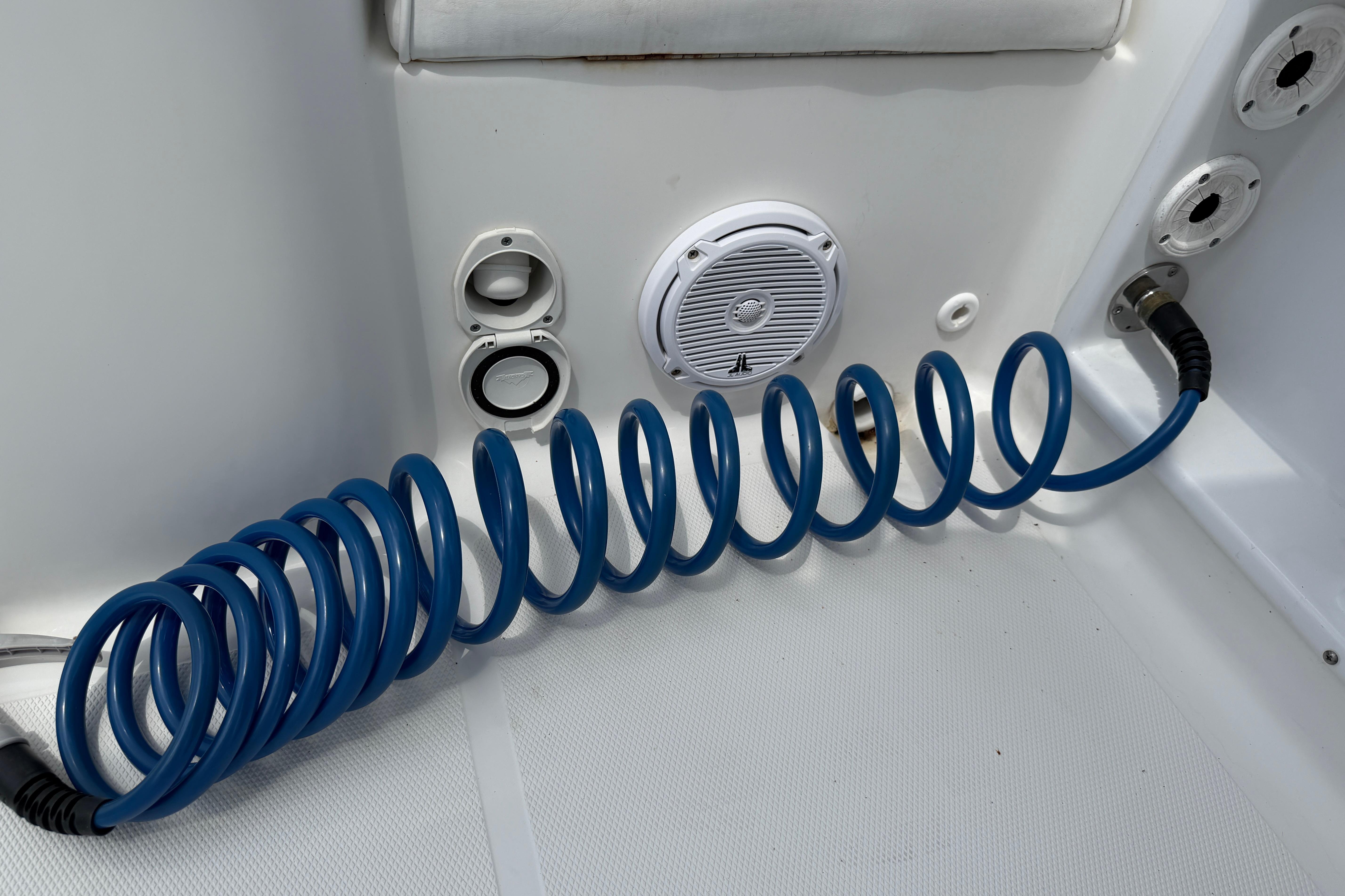 Coiled blue hose on 2015 Sea Hunt Triton 225 boat deck with speaker and fittings.