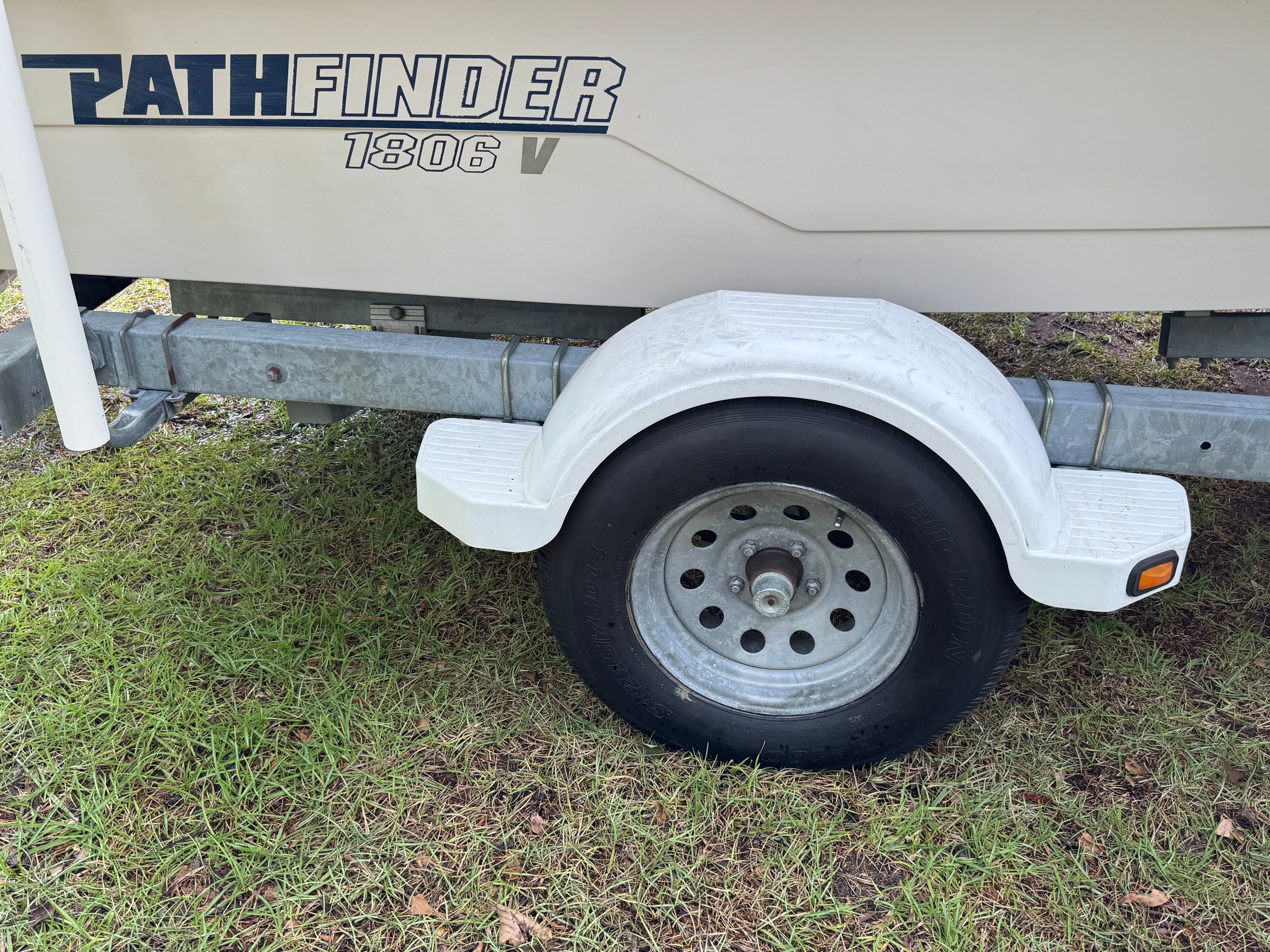 Close-up of a boat trailer with a white fender and black tire.
