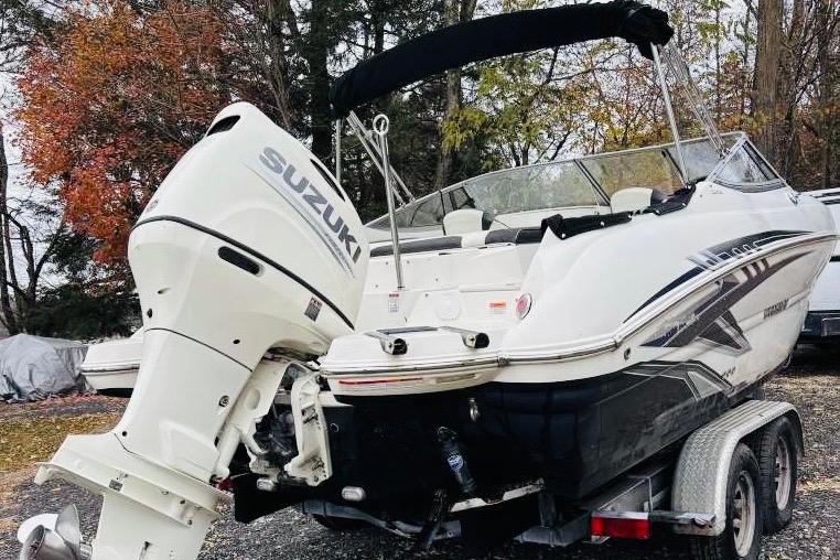 2018 Stingray 214 LR boat with Suzuki outboard motor on trailer, surrounded by autumn trees.