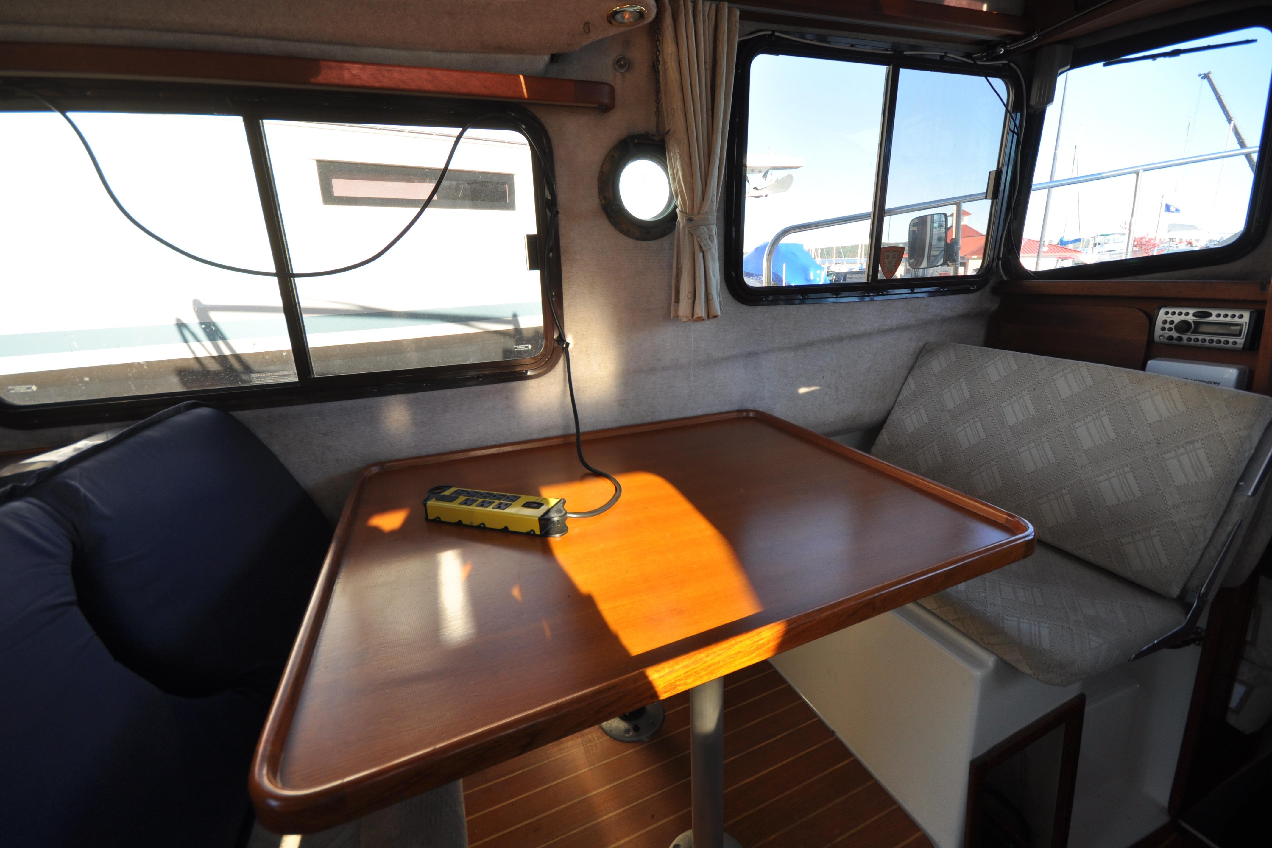 Interior of 2007 Ranger Tug R-25 with wooden table and cushioned seating.