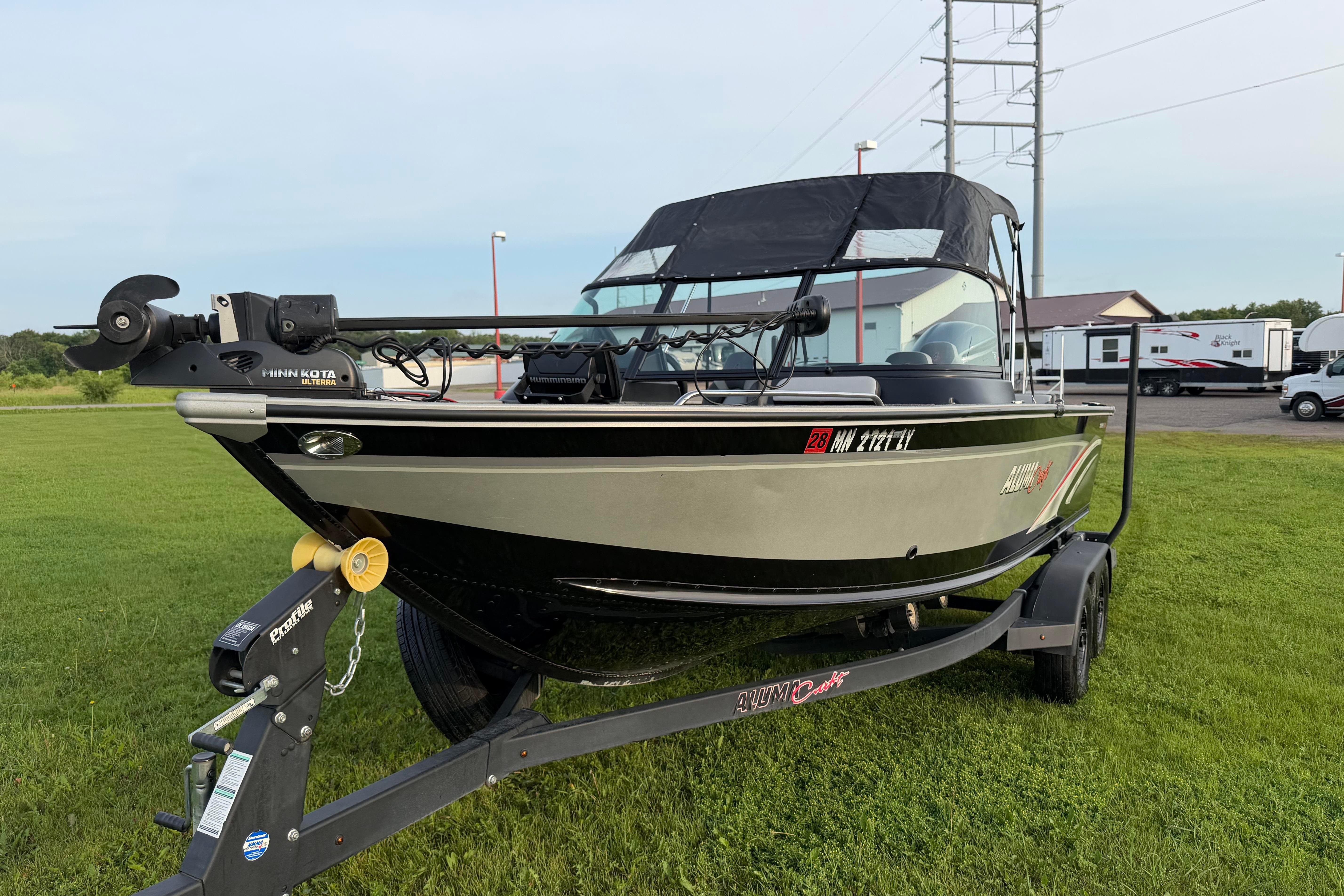 2019 Alumacraft Trophy 205 boat on trailer, parked on grass, with Minn Kota trolling motor.
