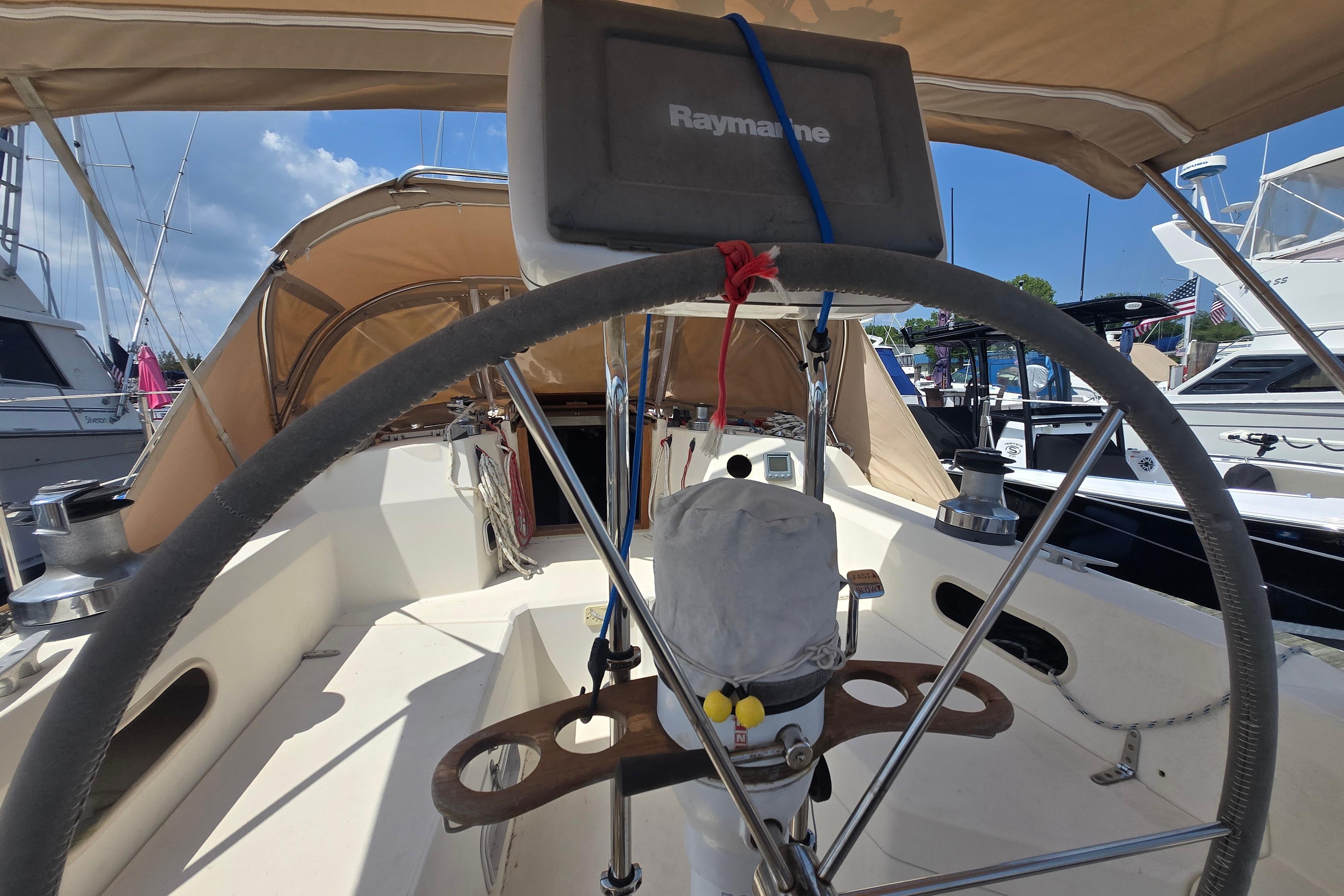 Cockpit view of a 1988 Sabre 38 sailboat with steering wheel and navigation equipment.