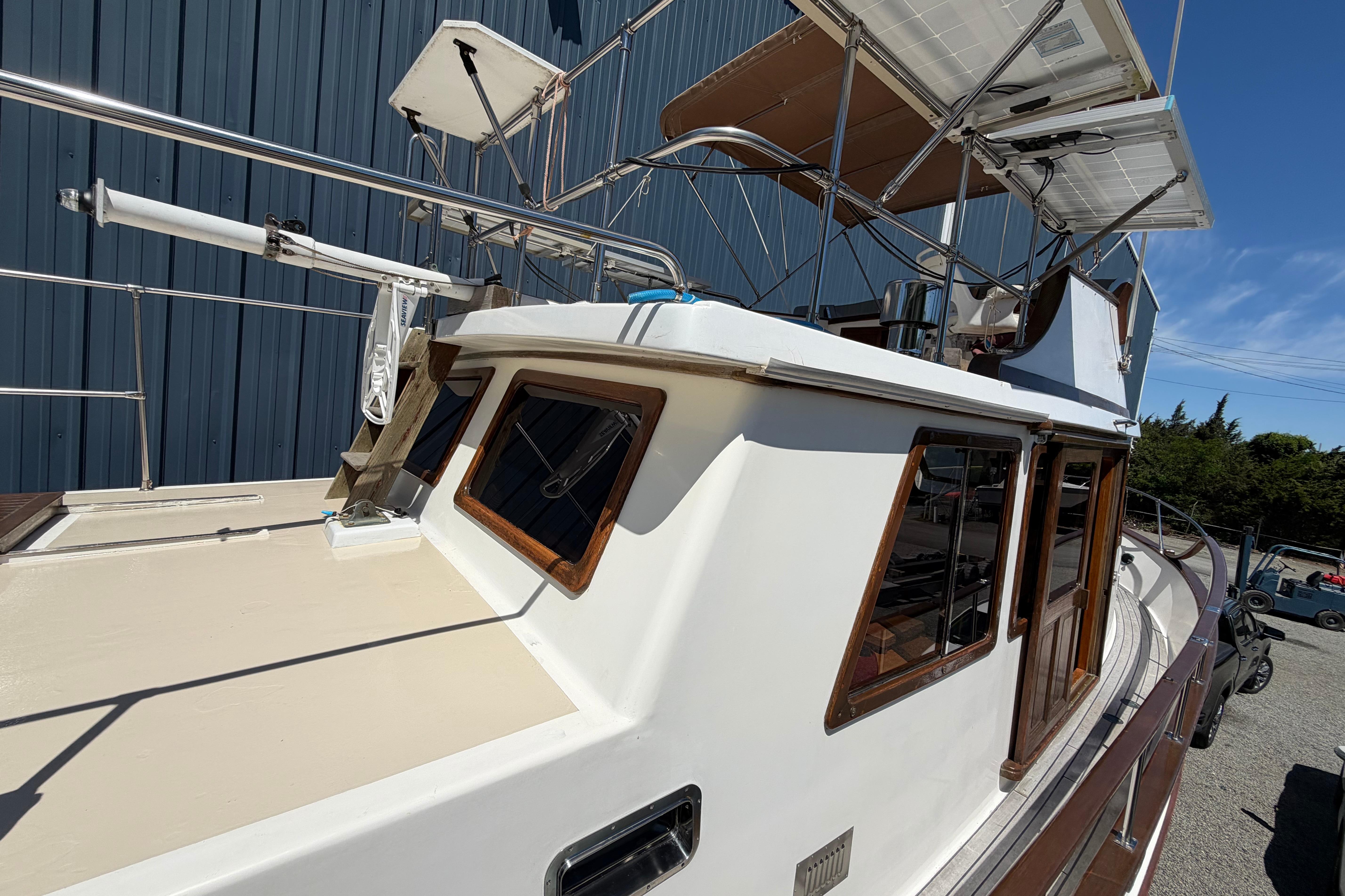 1987 Marine Trader 36 yacht with solar panels, docked near a blue building.