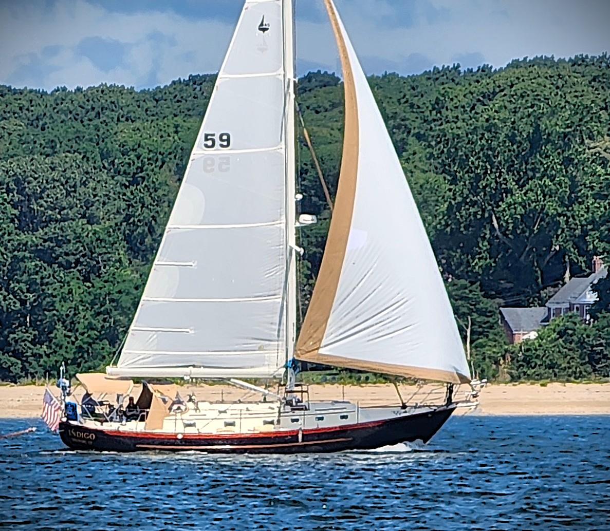 Sailboat Pacific Seacraft 40, 2005 model, sailing near a forested shoreline.