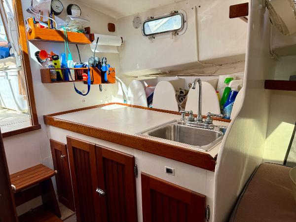 1978 Dyer 29 Trunk Cabin interior with sink, wooden cabinets, and nautical equipment.
