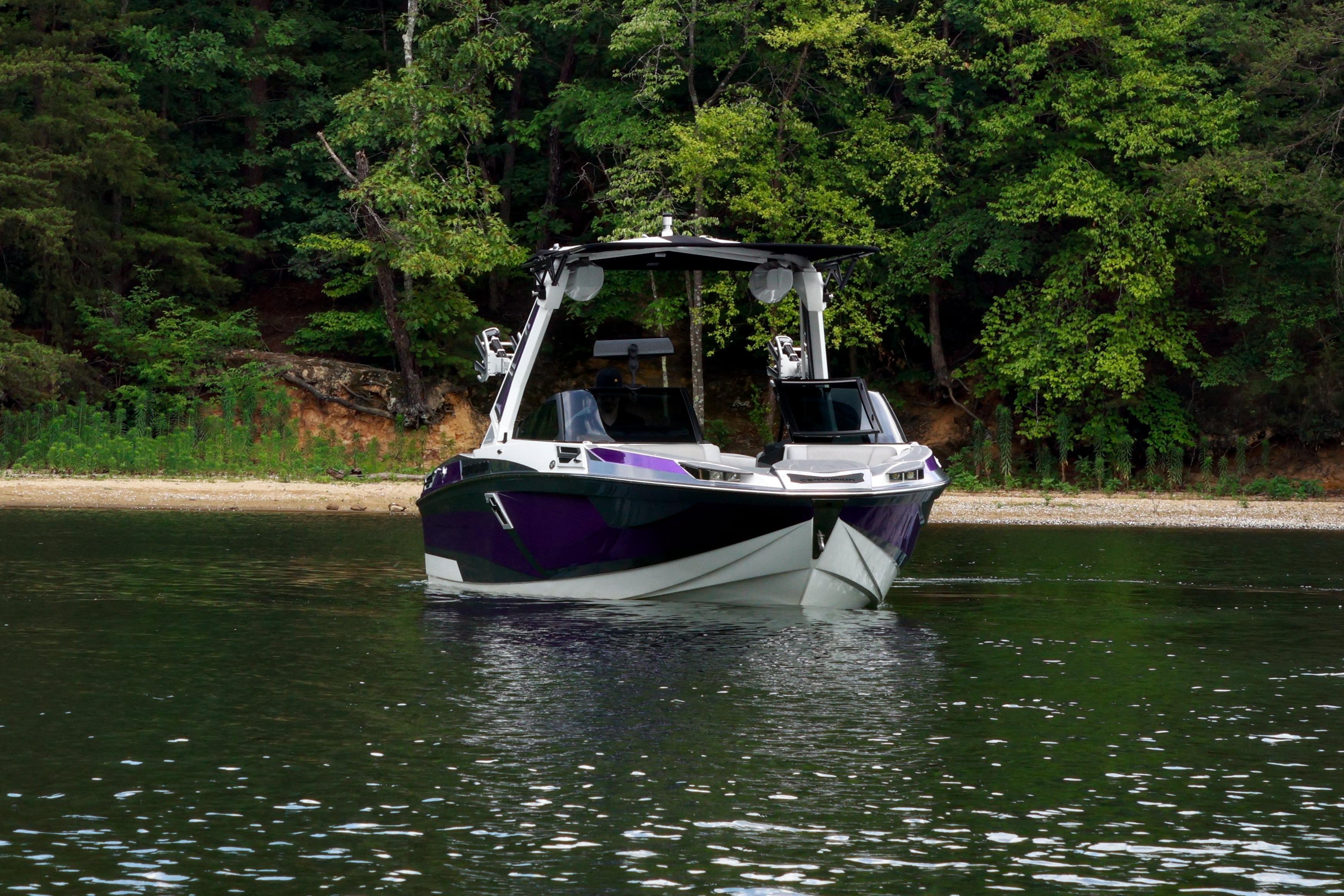 2022 Centurion Ri245 boat on calm water near a forested shoreline.