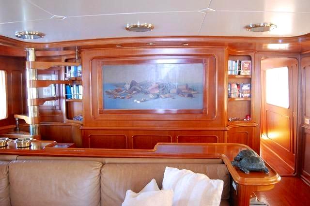 Luxurious wooden interior of 1964 Custom Hall Russell & Co 34 yacht with artwork and bookshelves.