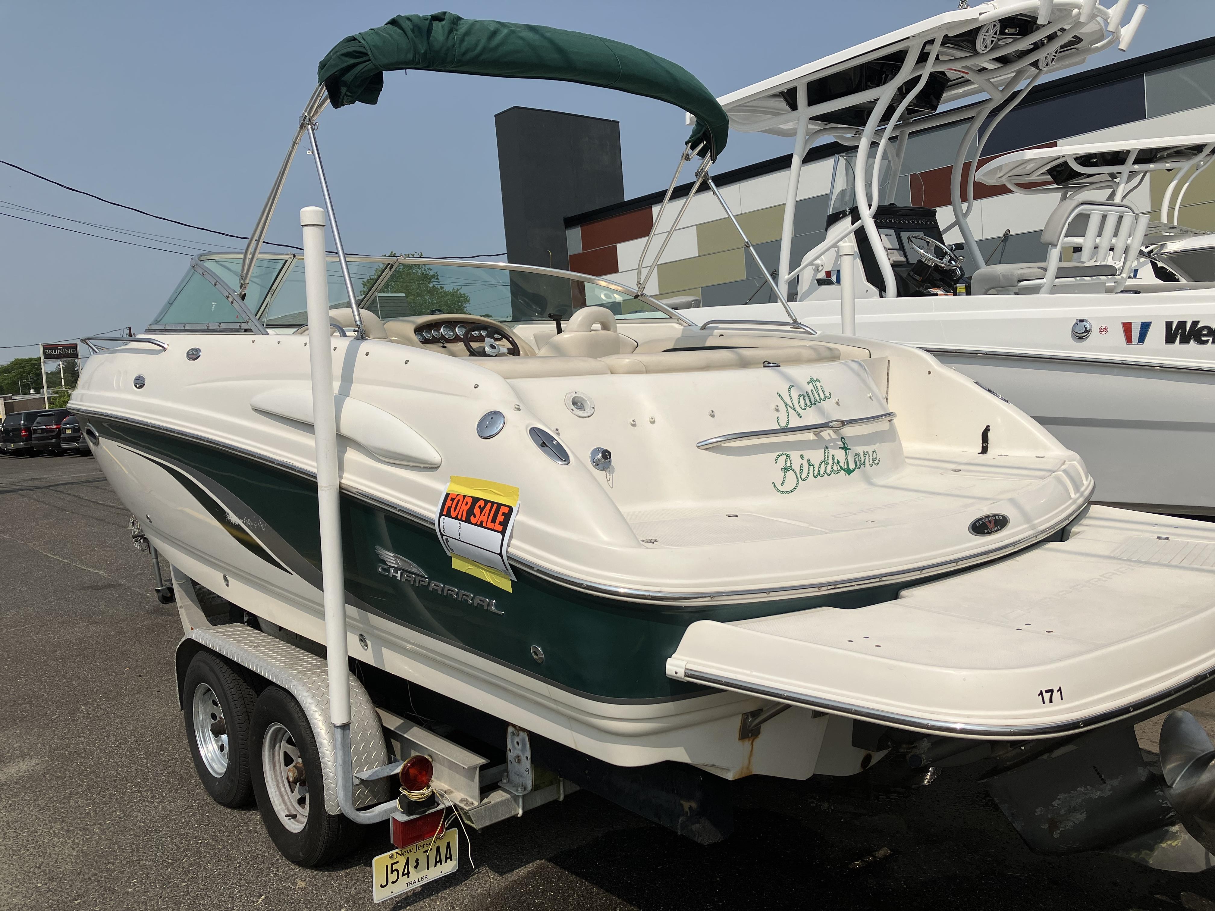 A 2001 Chaparral 235 SSi boat on a trailer. It features a green canopy.