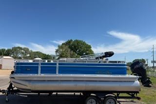 2026 Sun Tracker Fishin' Barge 20 DLX pontoon boat on trailer under clear blue sky.