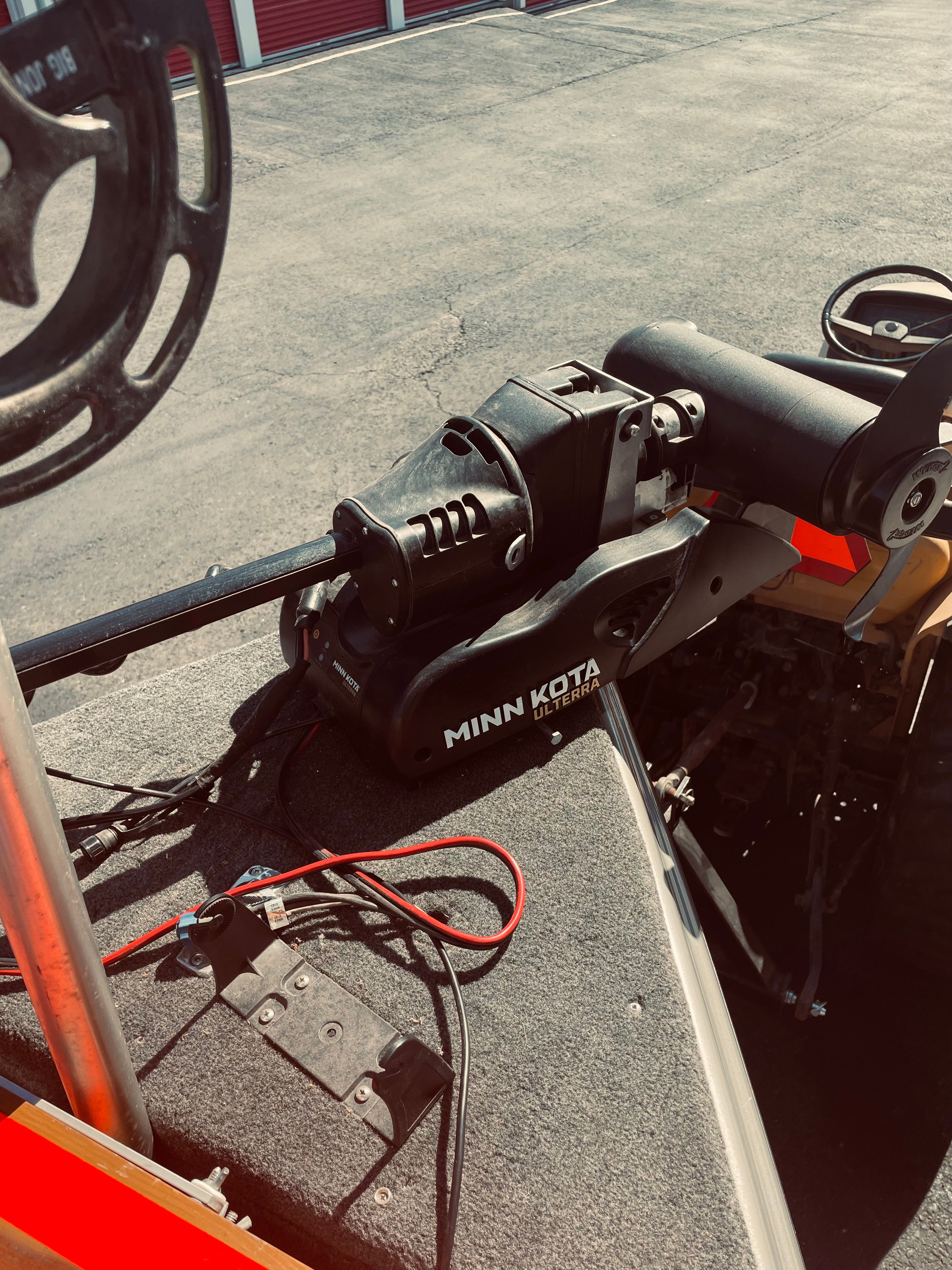 A Minn Kota trolling motor is mounted on a boat parked in a lot.