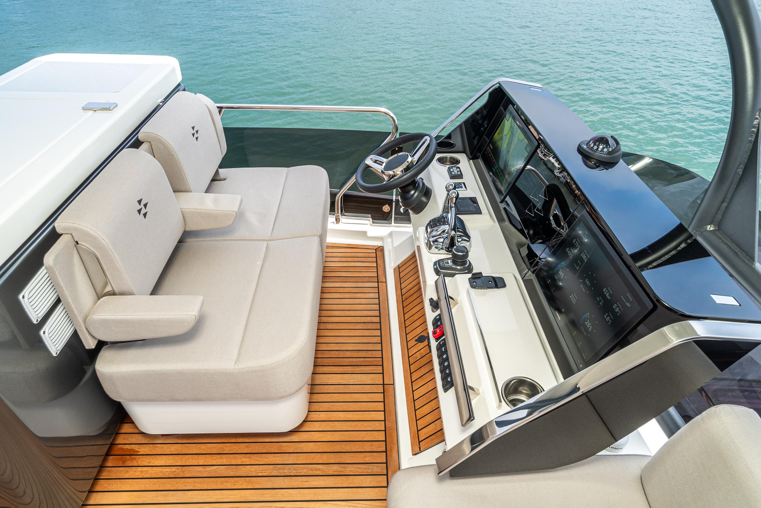 2024 Prestige X60 yacht helm with modern controls and beige seating, overlooking the ocean.