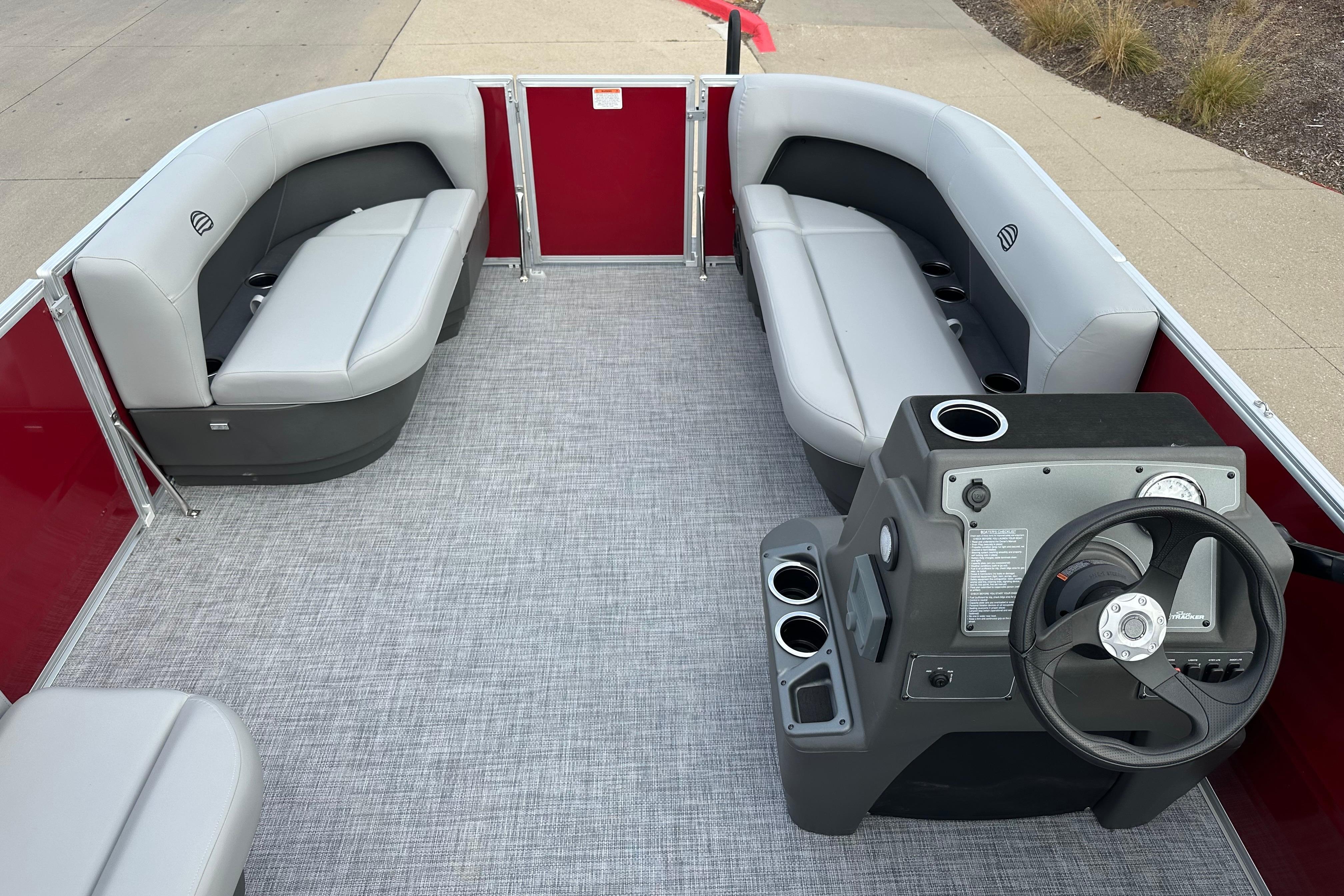 2026 Sun Tracker Party Barge 16 DLX interior with gray seating and steering console.