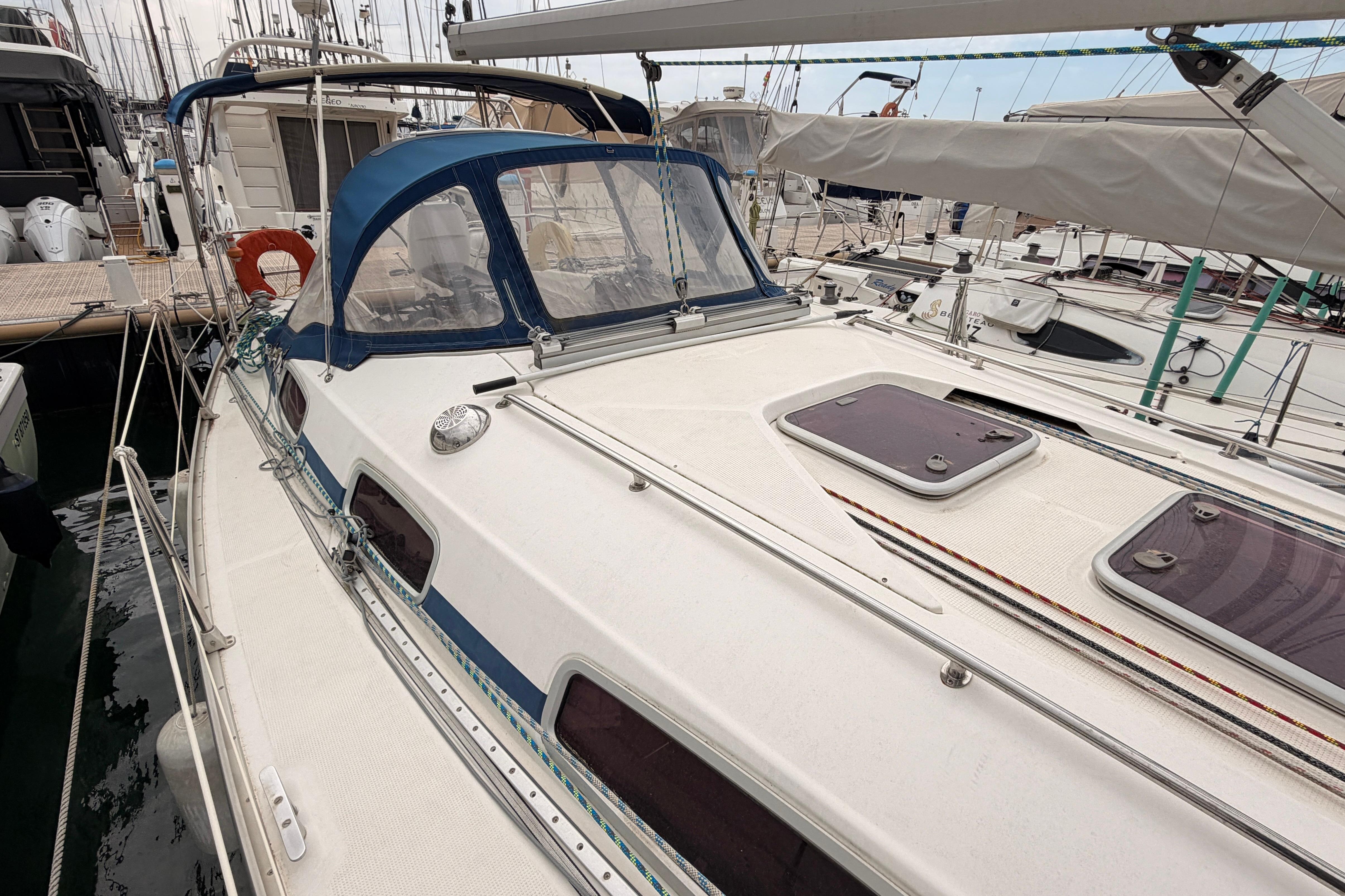 2009 Bavaria 34 Cruiser sailboat docked at marina, featuring blue canopy and deck hatches.