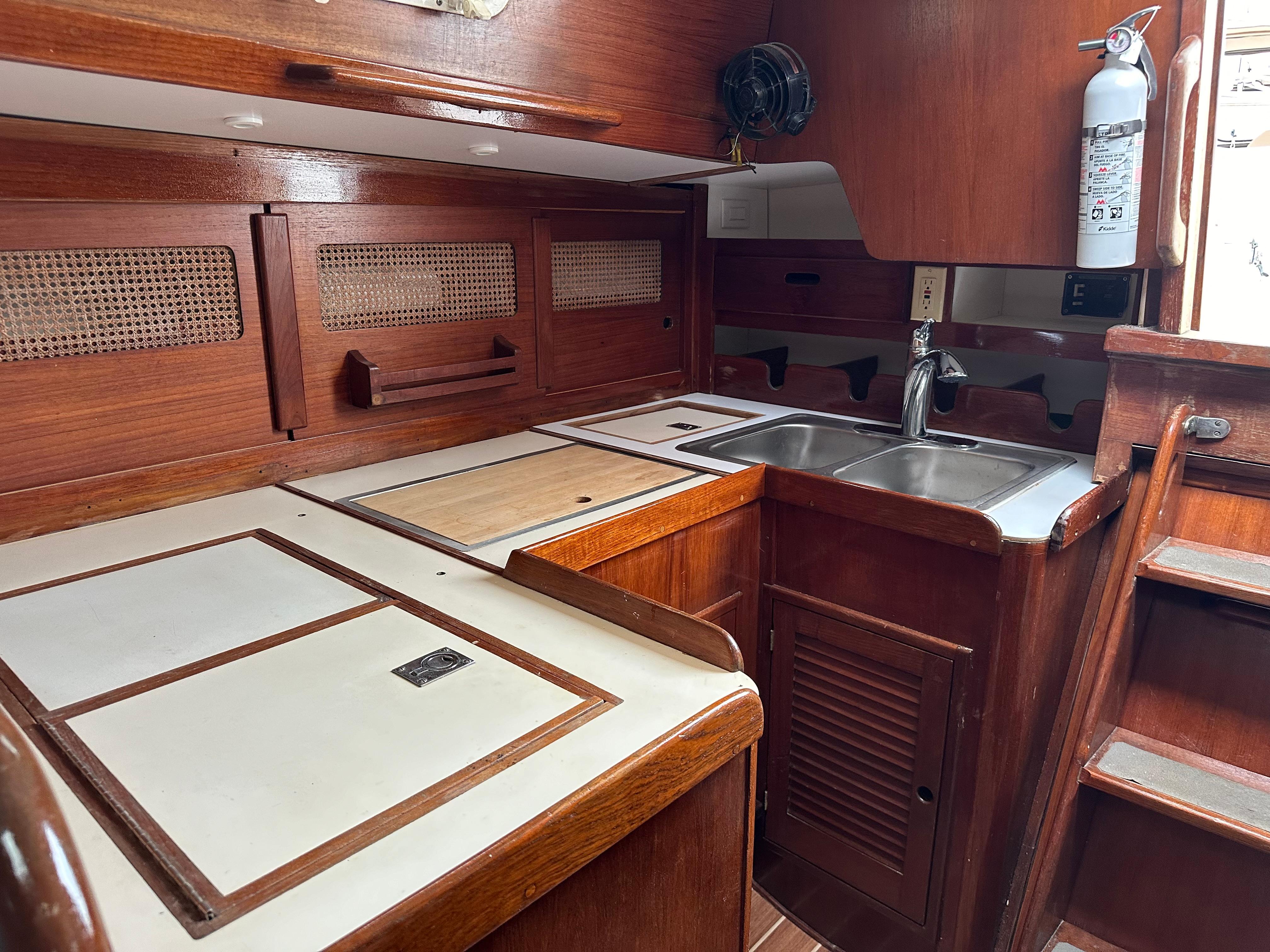 1981 Tartan 37 sloop interior kitchen with wooden cabinetry and stainless steel sink.