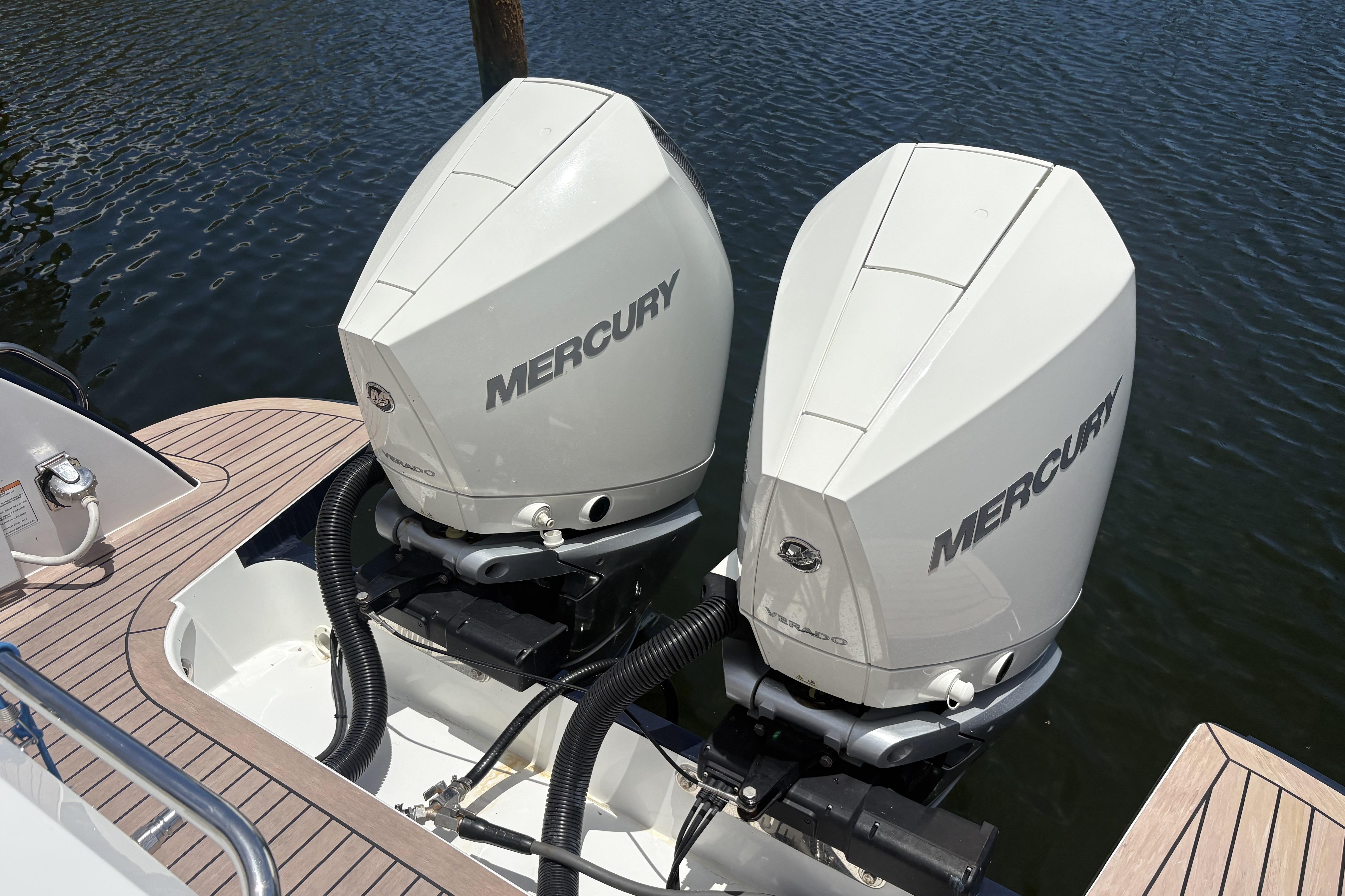 Twin Mercury outboard engines on a 2024 MJM 35z boat, docked on calm water.