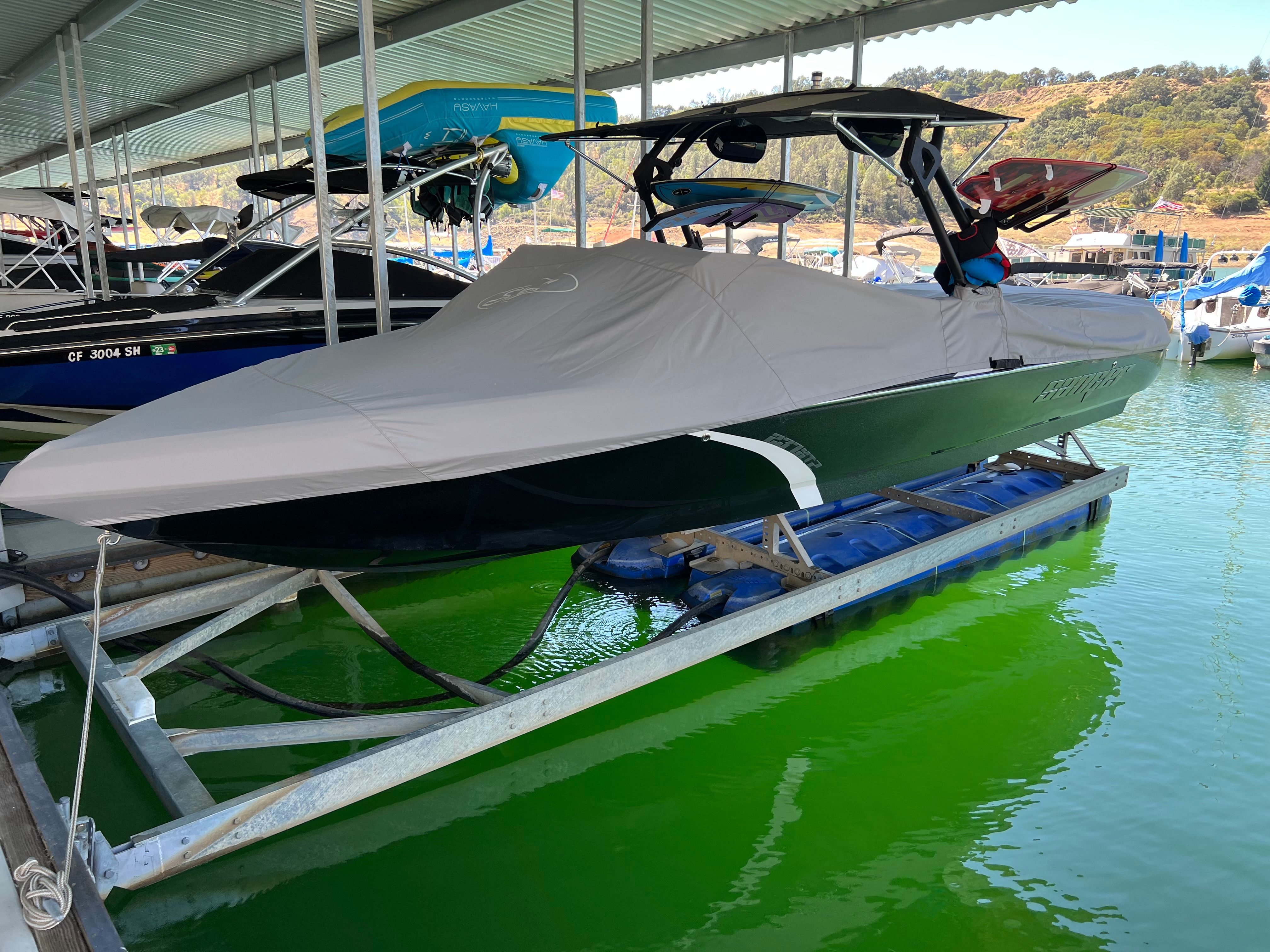 A 2020 Sanger V237 XTZ is on a boat lift in a covered dock.