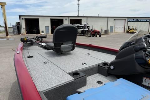 2024 Tracker Pro Team 175 TXW boat with red trim, parked near a workshop.