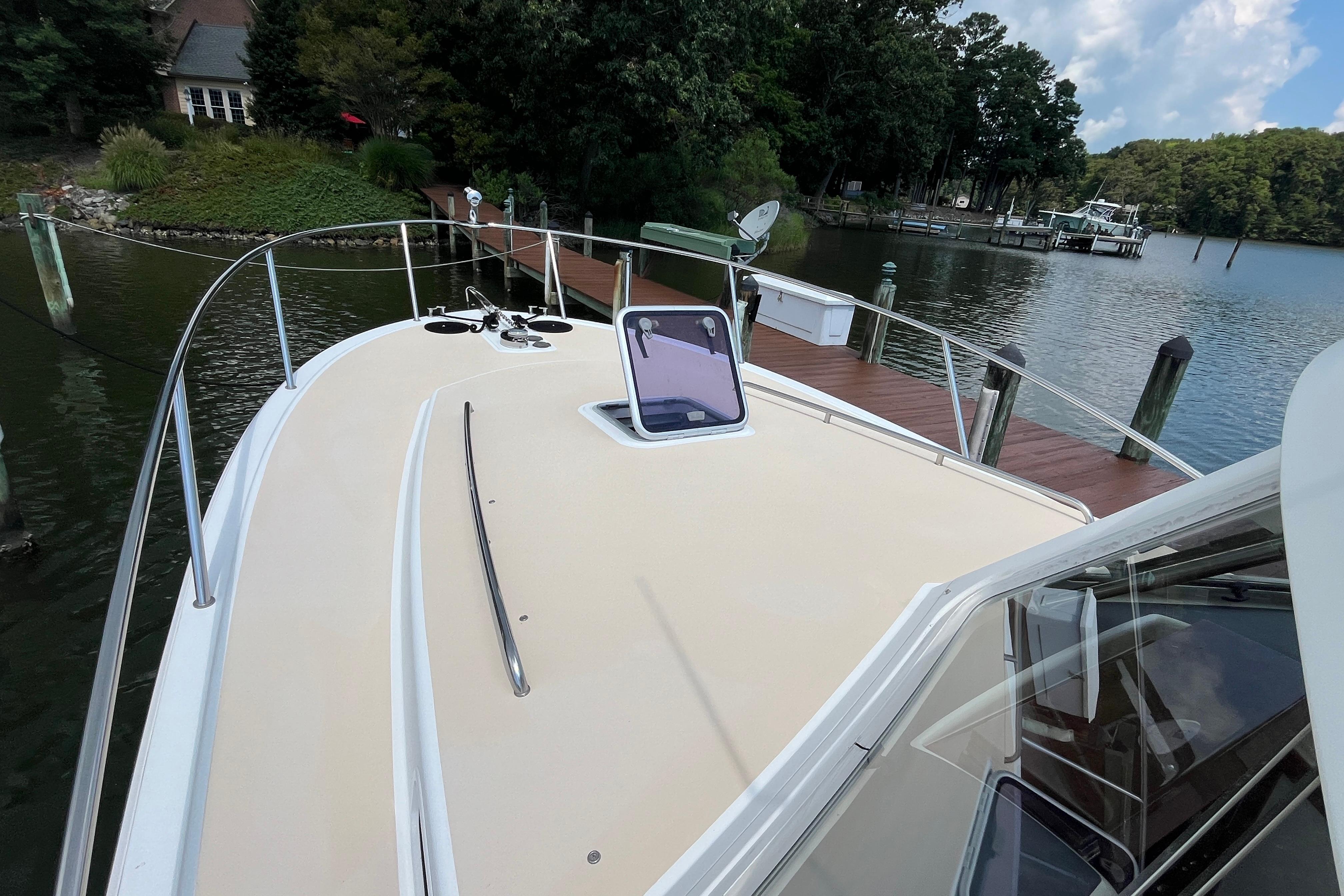 2006 MJM 34z boat docked by a scenic lakeside with lush greenery.