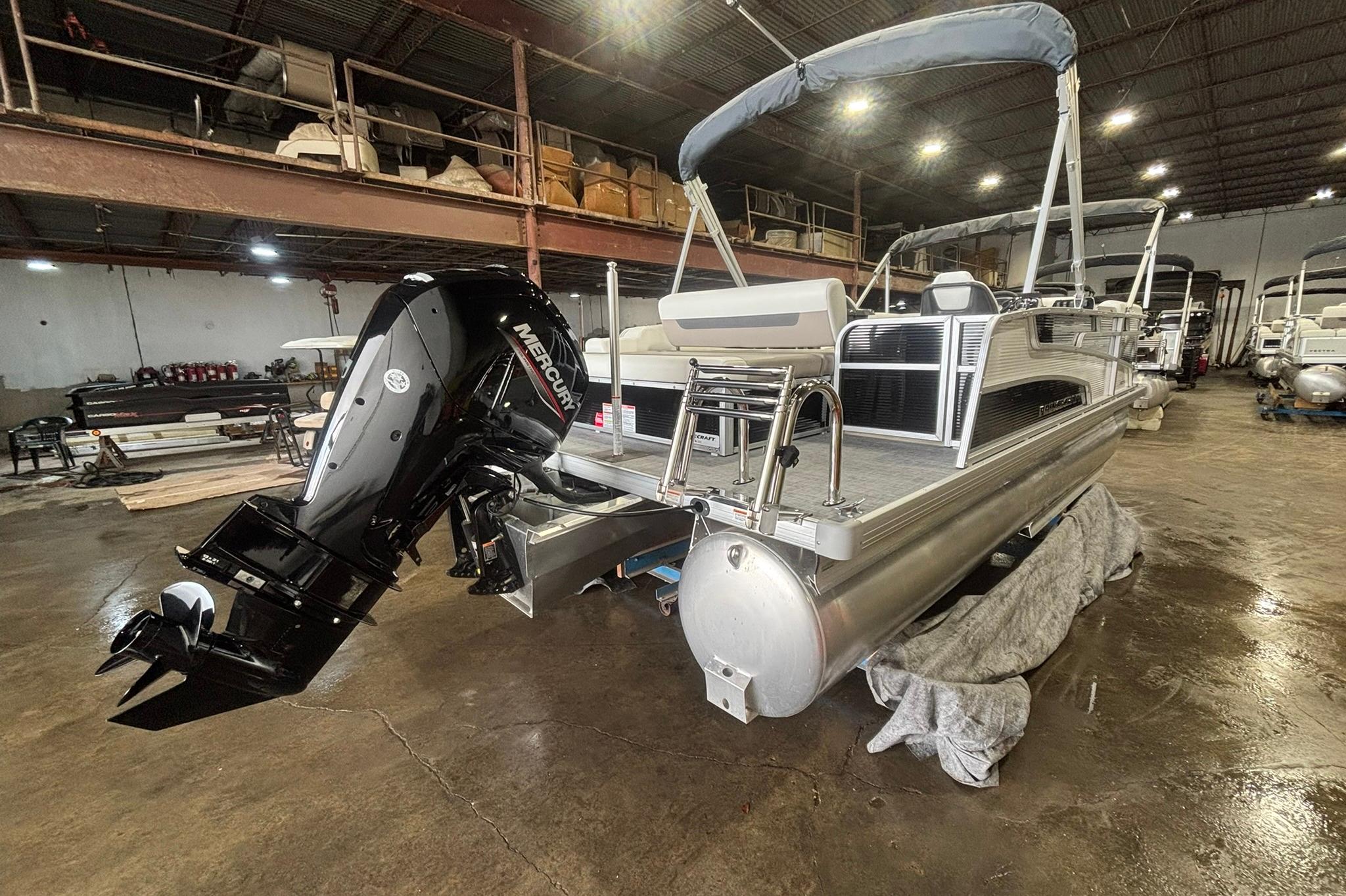 2025 Princecraft Vectra 21 RL pontoon boat with Mercury outboard in a warehouse setting.