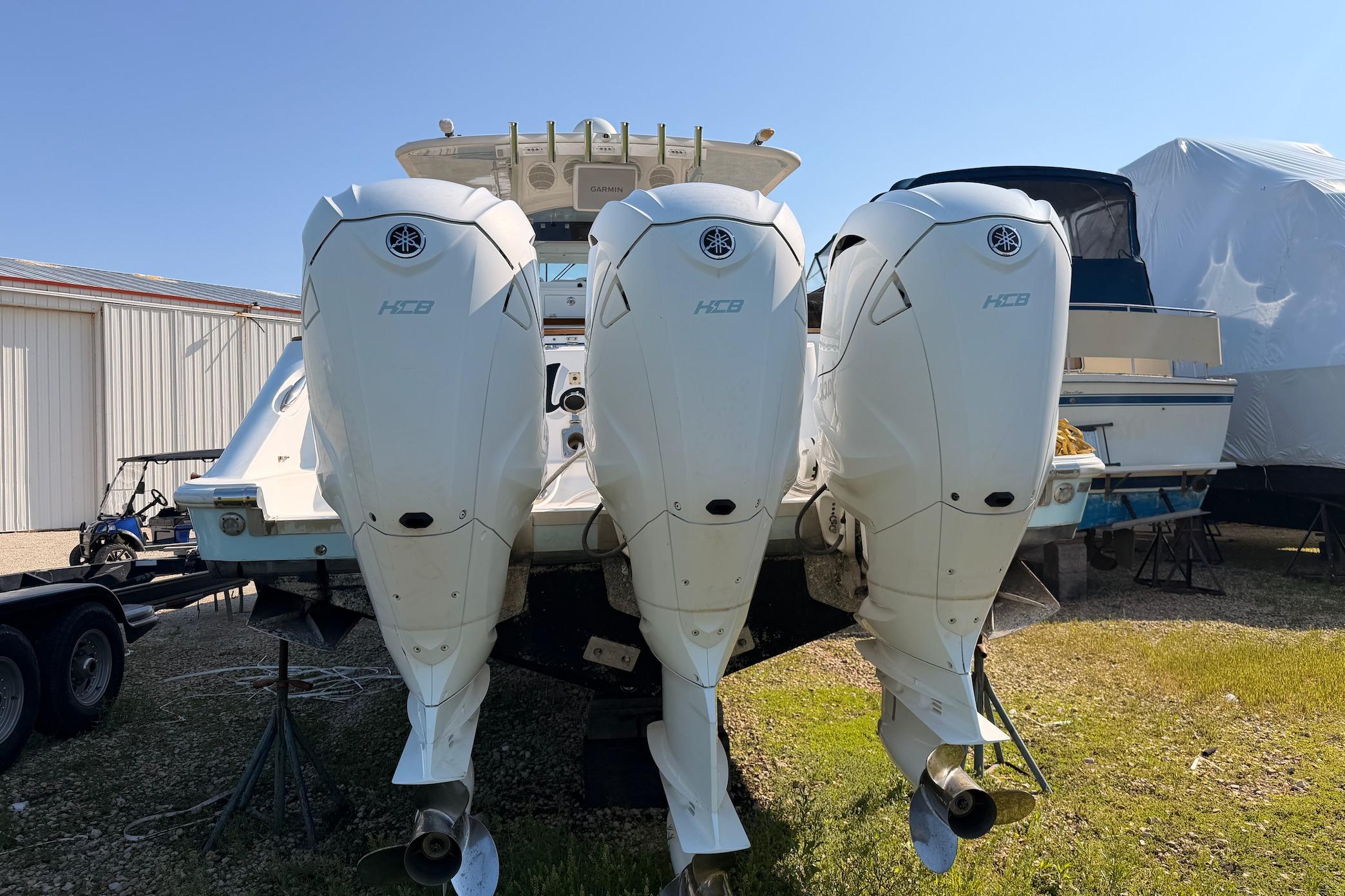 2022 HCB 42 Lujo boat with triple outboard engines, parked outdoors.