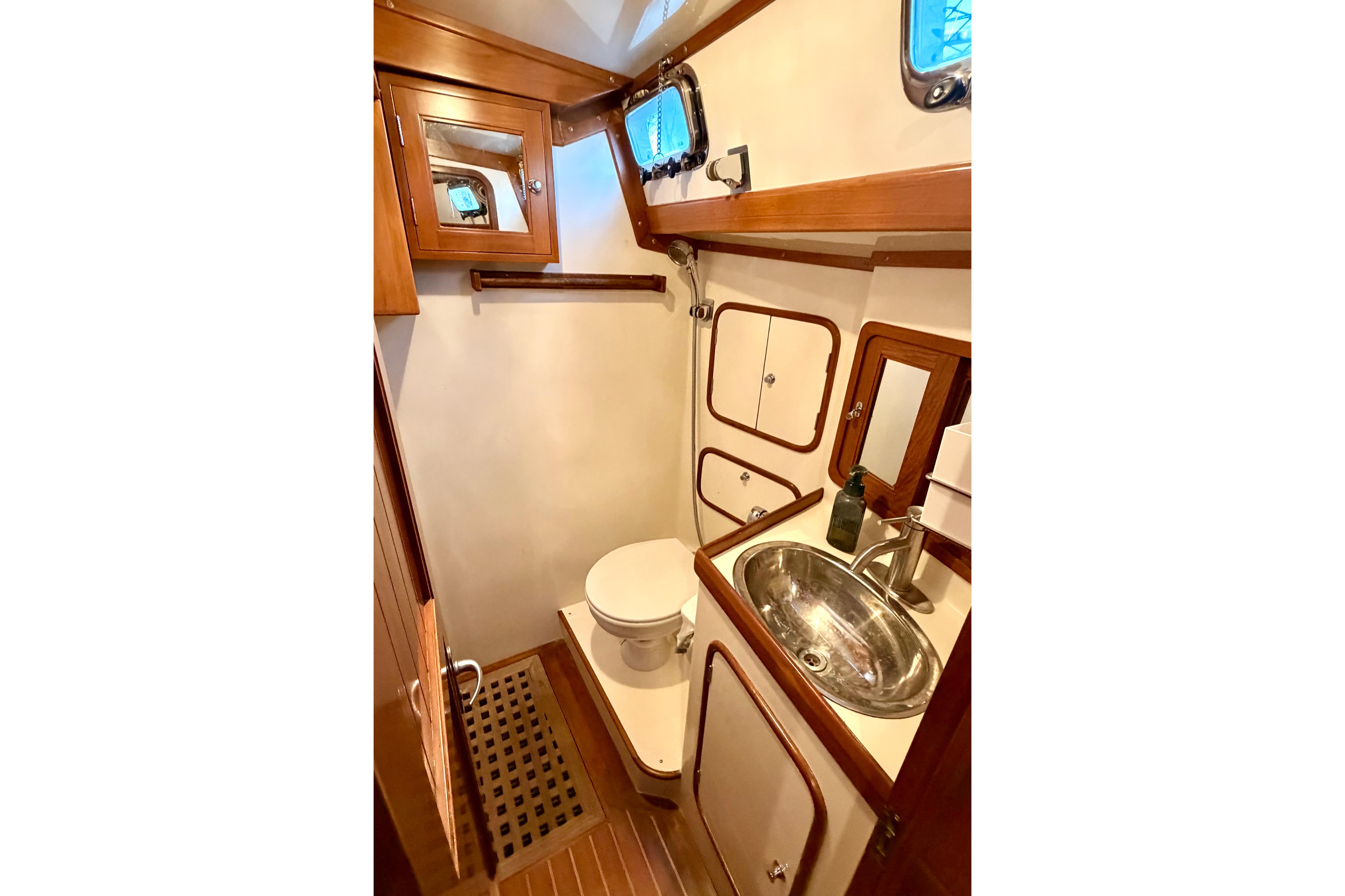 Bathroom interior of 2001 Tayana Vancouver 42 yacht, featuring wood accents and stainless steel sink.