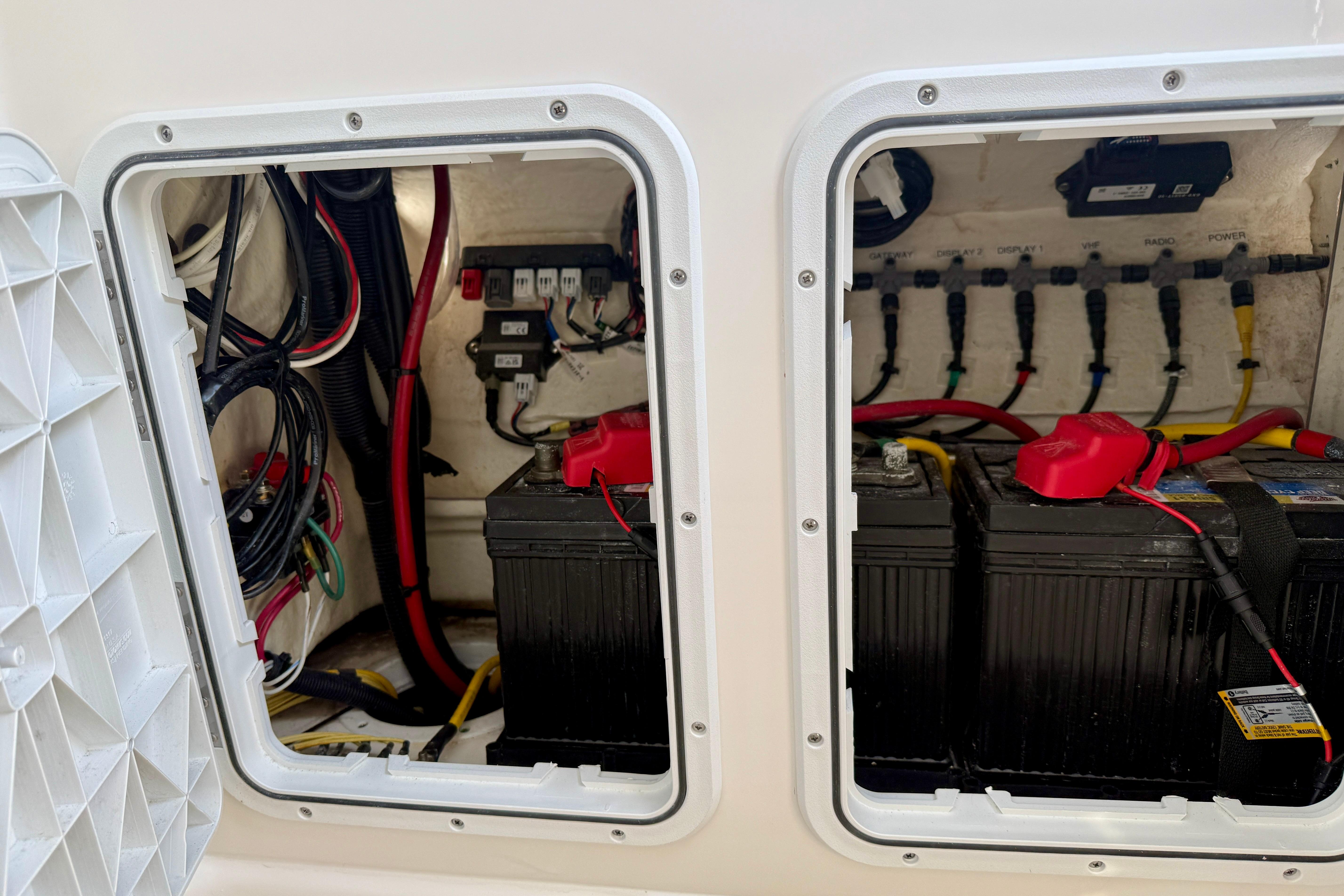 Electrical compartment of 2023 Edgewater 245CC boat, featuring batteries and wiring.