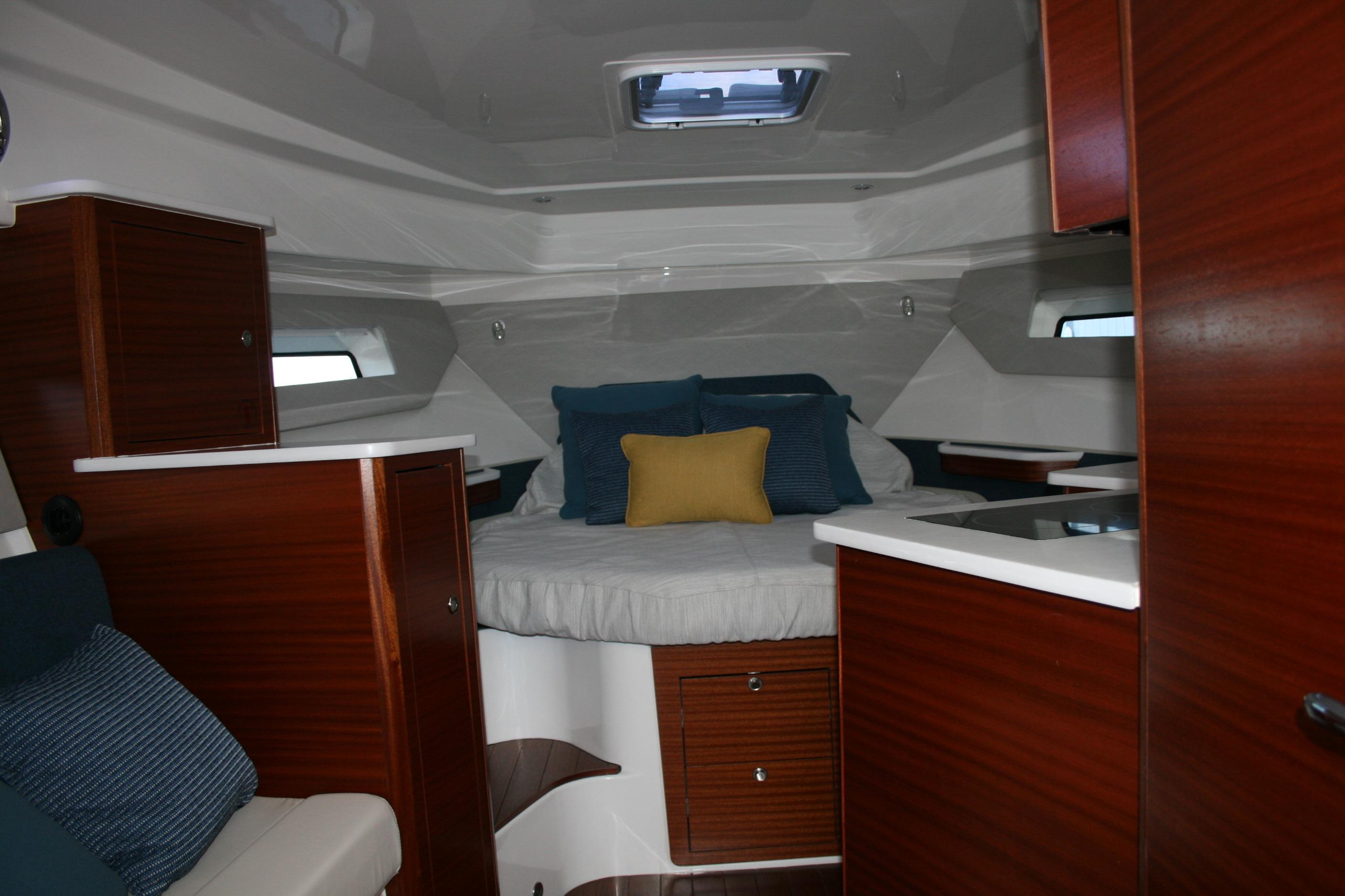 Luxurious cabin interior of 2025 Pursuit OS 405 Offshore boat with cozy bedding.