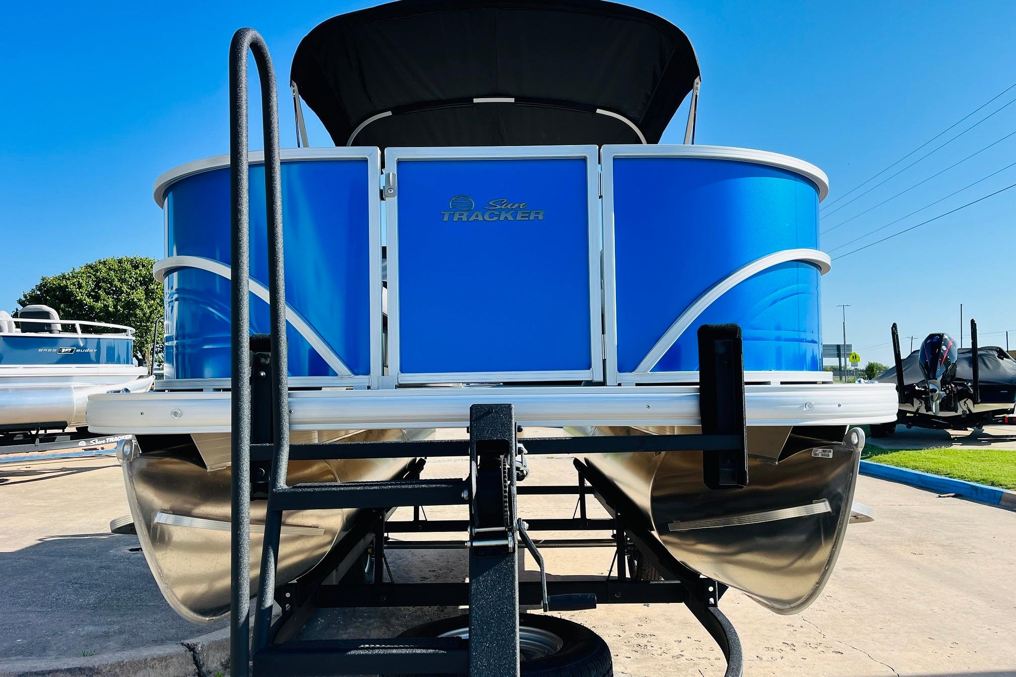 2026 Sun Tracker Party Barge 18 DLX pontoon boat, vibrant blue exterior, docked outdoors.