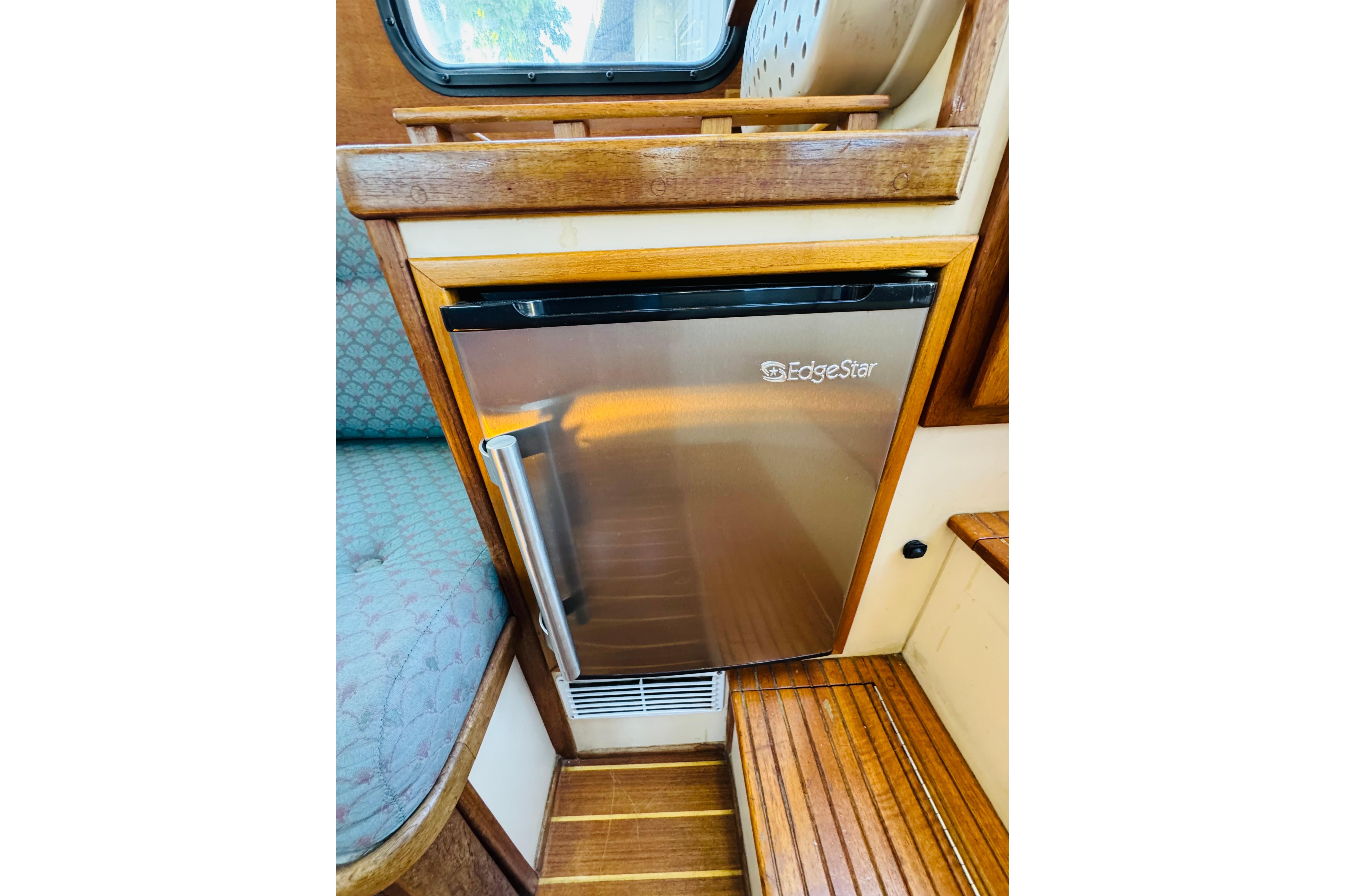 EdgeStar fridge in 1996 Nordic Tug 32 boat interior, featuring wood accents and seating.