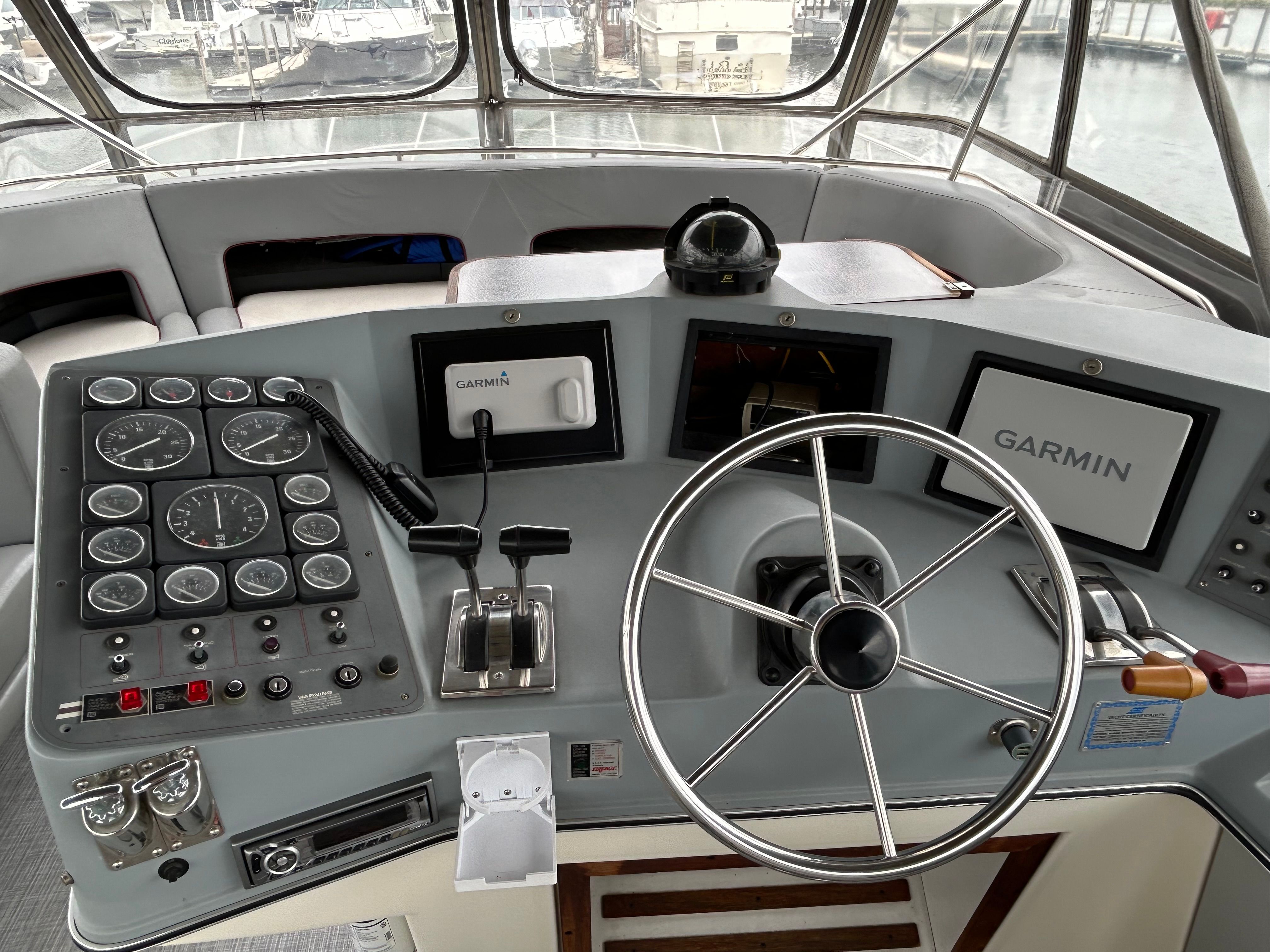 The image shows the helm of a 1988 Cruisers Yachts 4280 Express Bridge with modern Garmin devices.