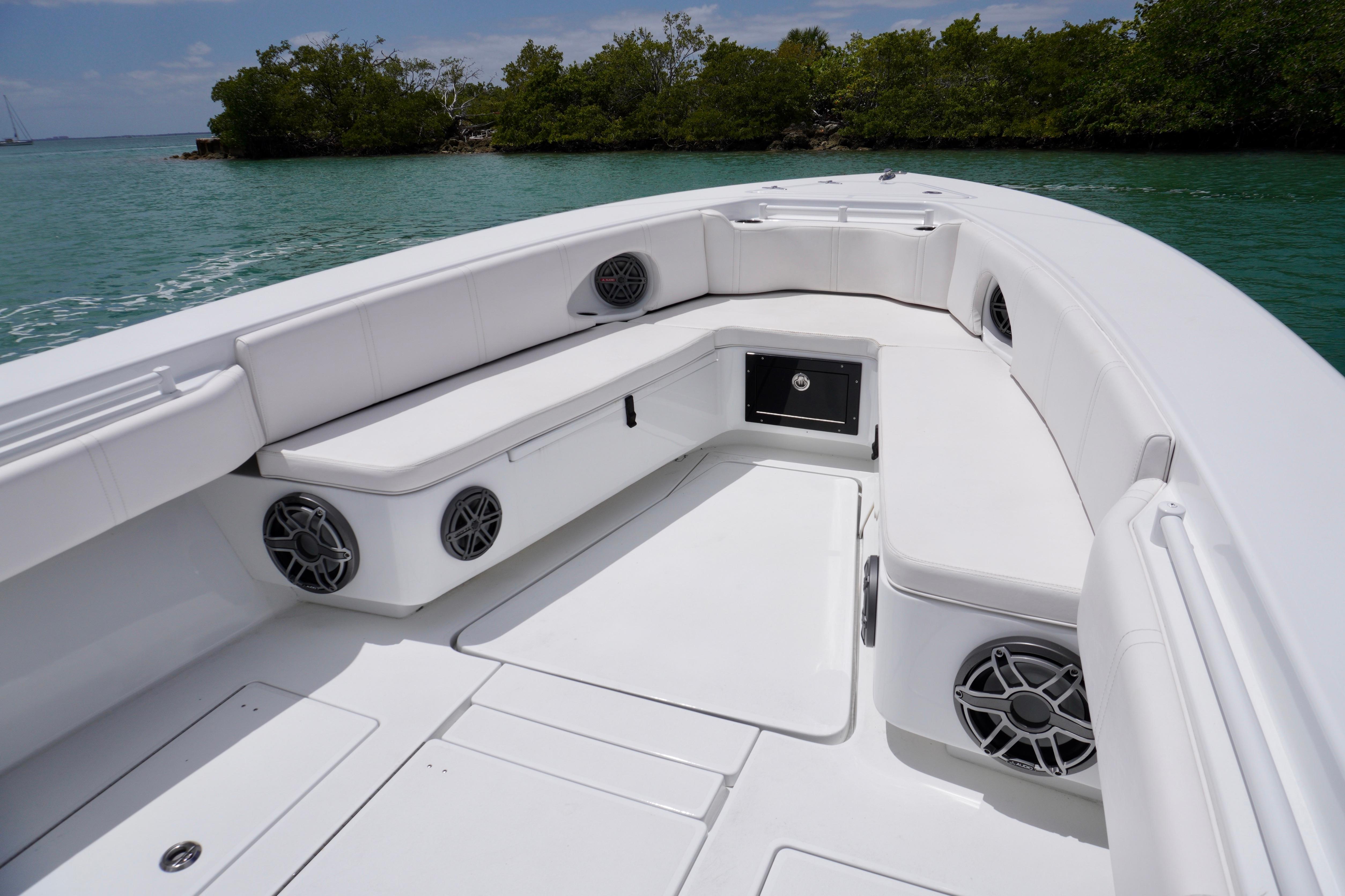2013 Contender 35 LS boat interior with white seating and speakers, near lush shoreline.