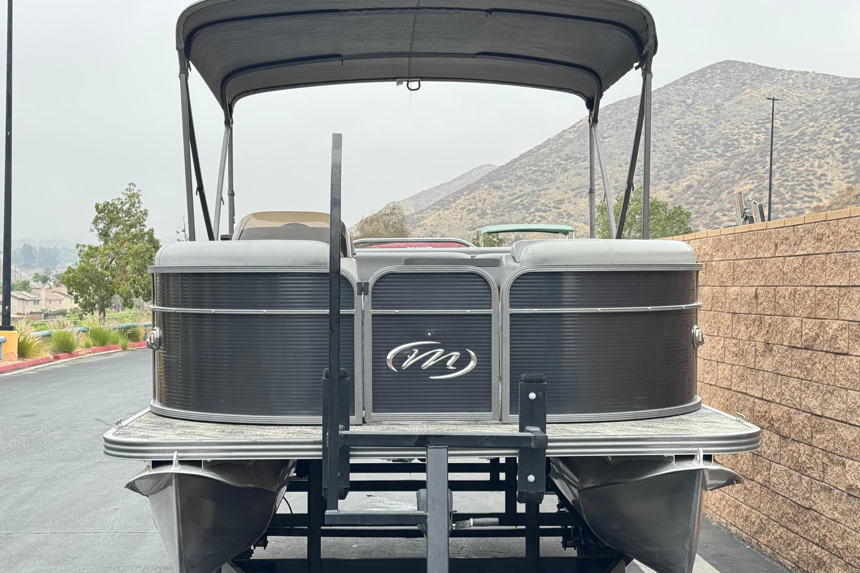 2020 Manitou 18 Aurora LE pontoon boat with canopy, parked near mountains.