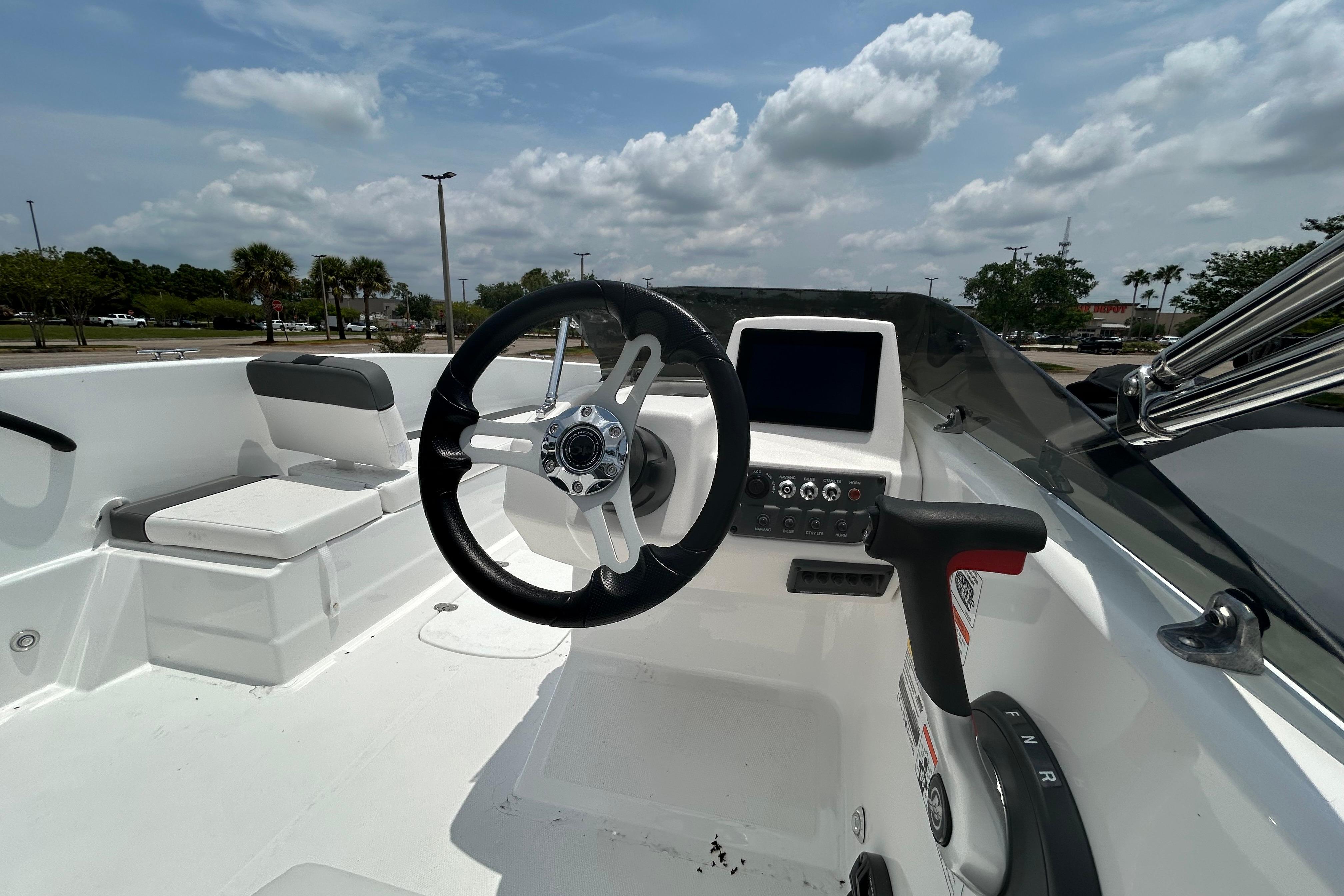 2026 Tahoe T18 boat interior with steering wheel and control panel under cloudy sky.