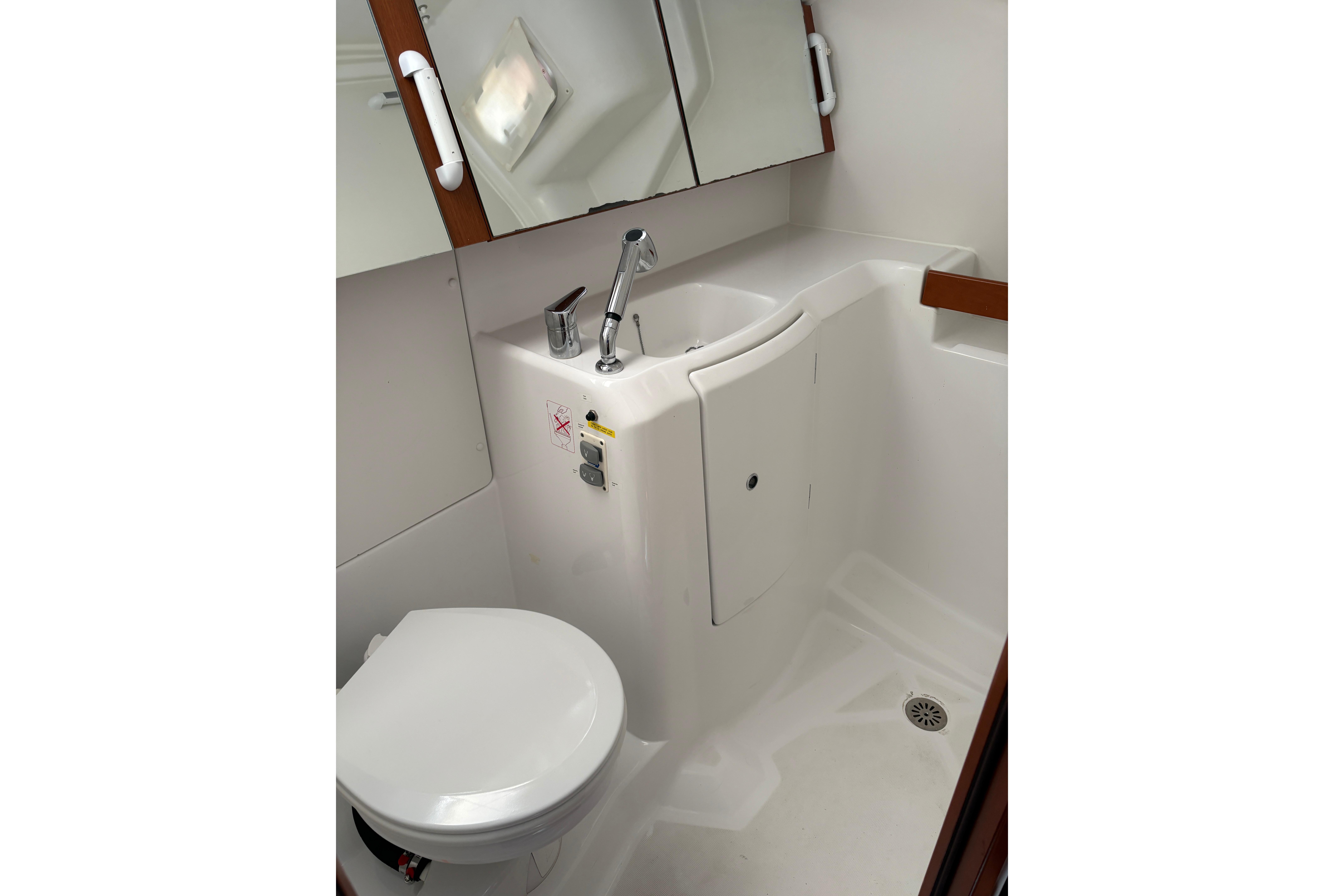 Compact bathroom in 2015 Beneteau Oceanis 34 yacht, featuring toilet, sink, and mirror.