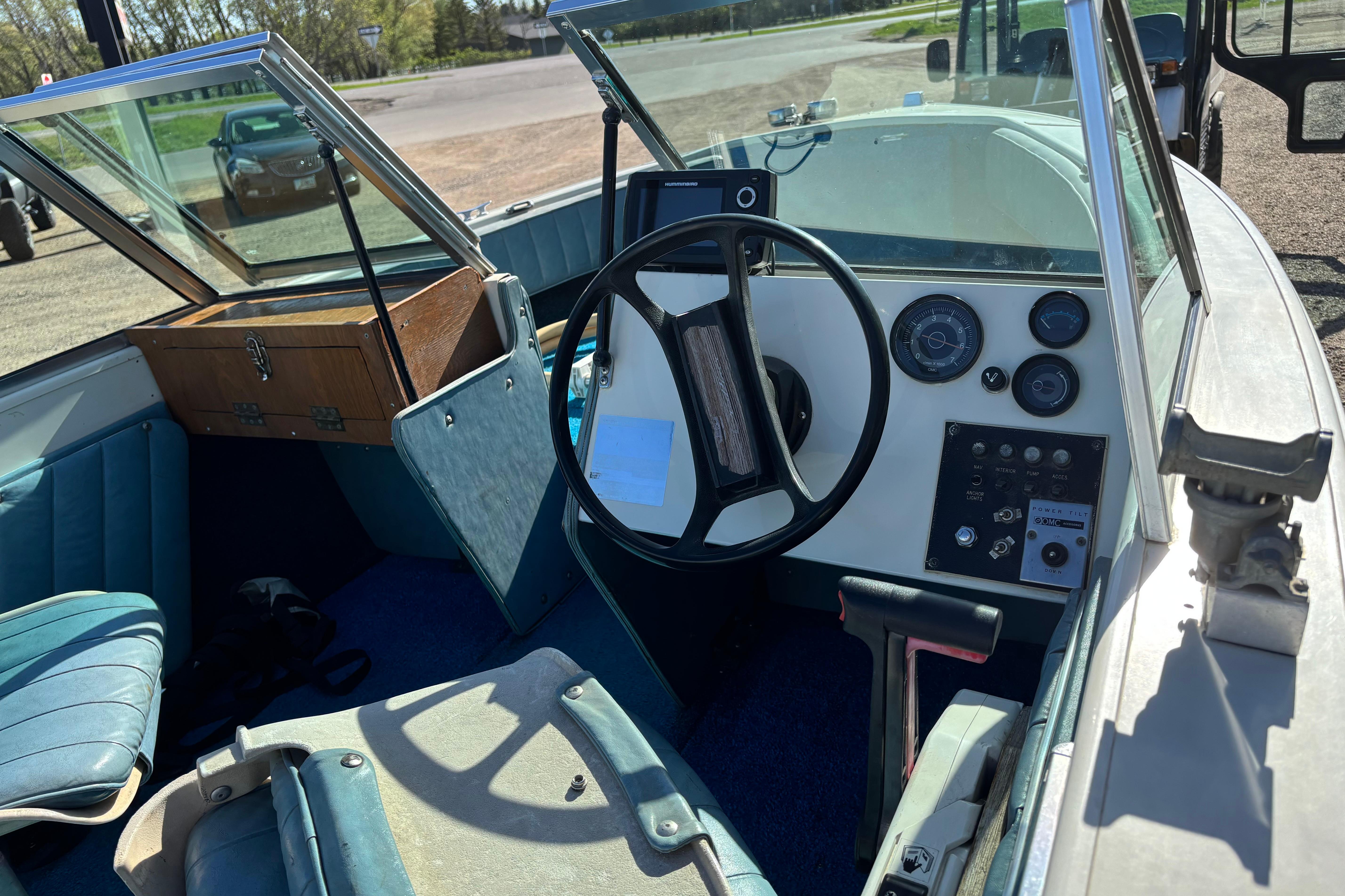 1983 Crestliner 16 boat interior with steering wheel, dashboard, and blue seating.