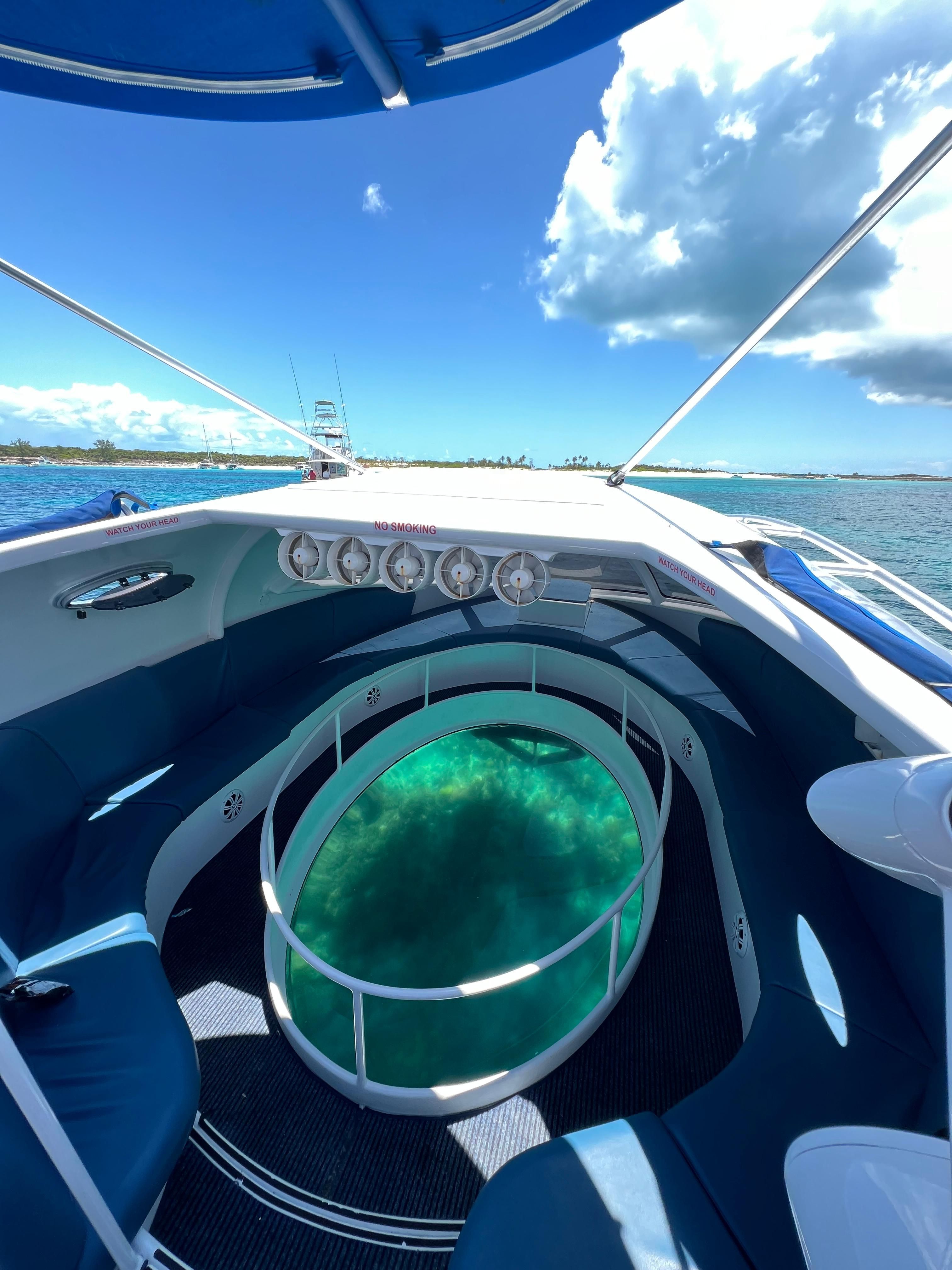 A modern boat with a glass bottom offers a view of the clear water below.