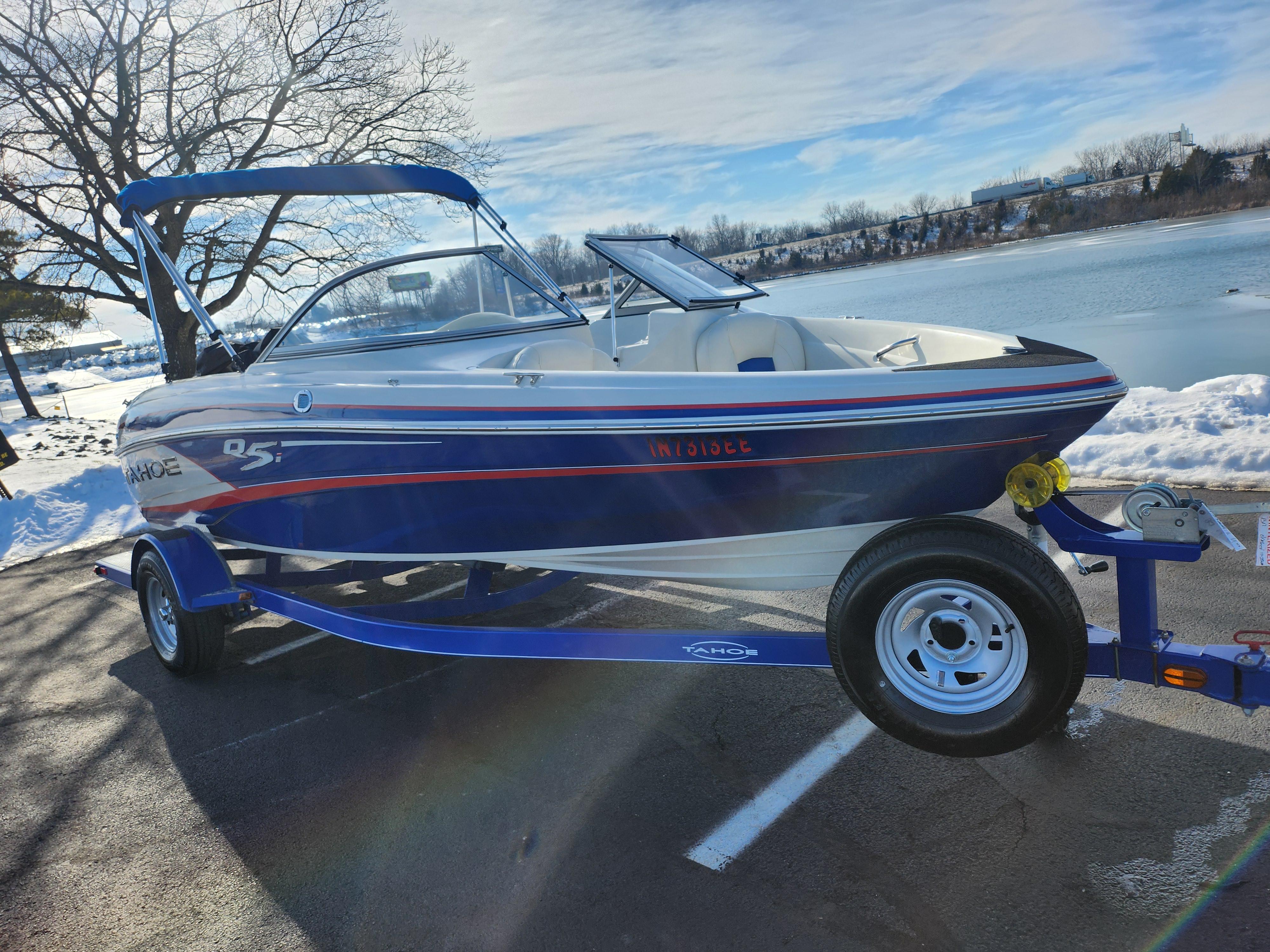2014 Tahoe Q5i SF boat on trailer by snowy lakeside.