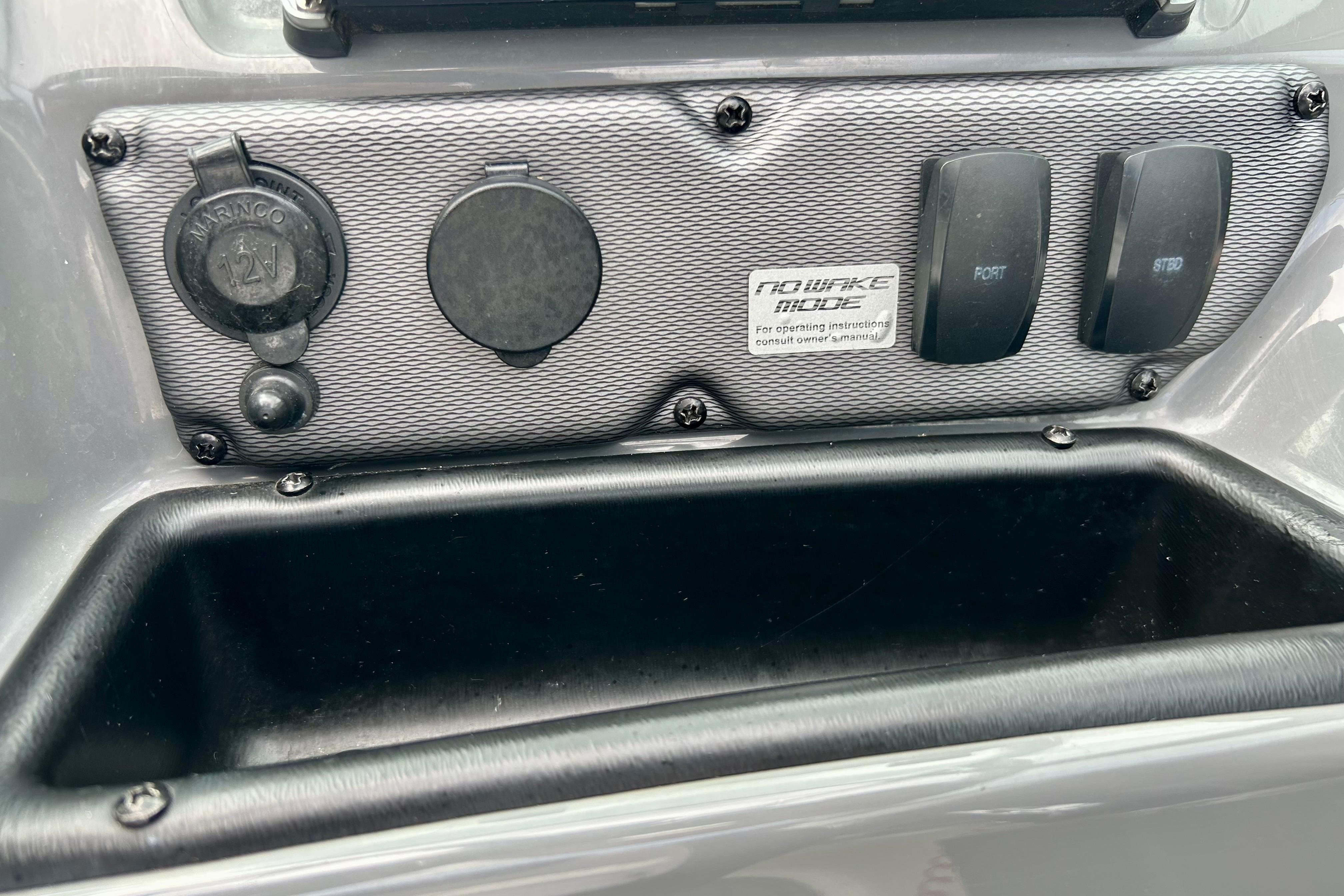 Control panel of a 2015 Yamaha Boats AR210, featuring switches and a 12V outlet.