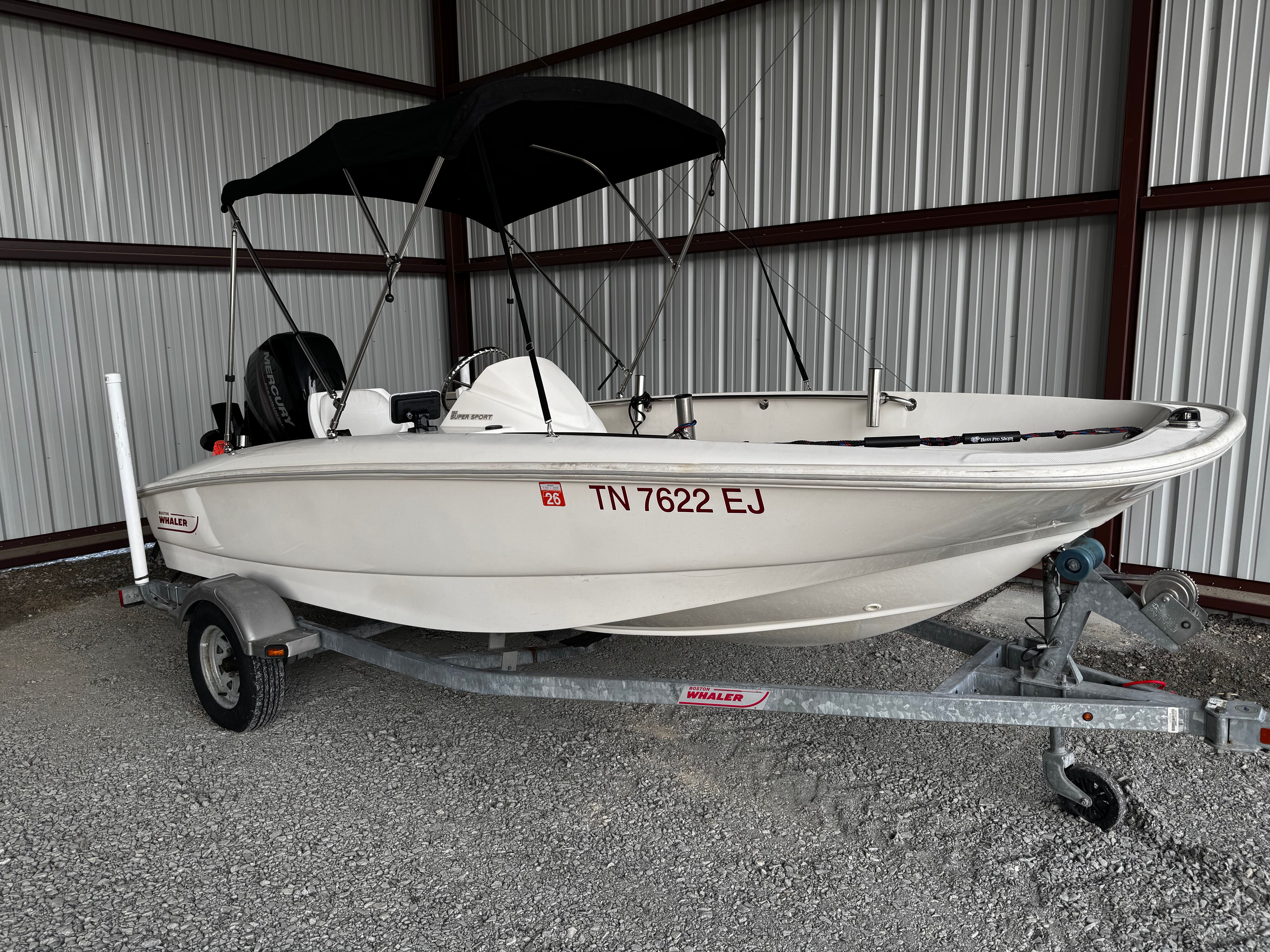 A 2015 Boston Whaler 150 Super Sport on a trailer in a warehouse.
