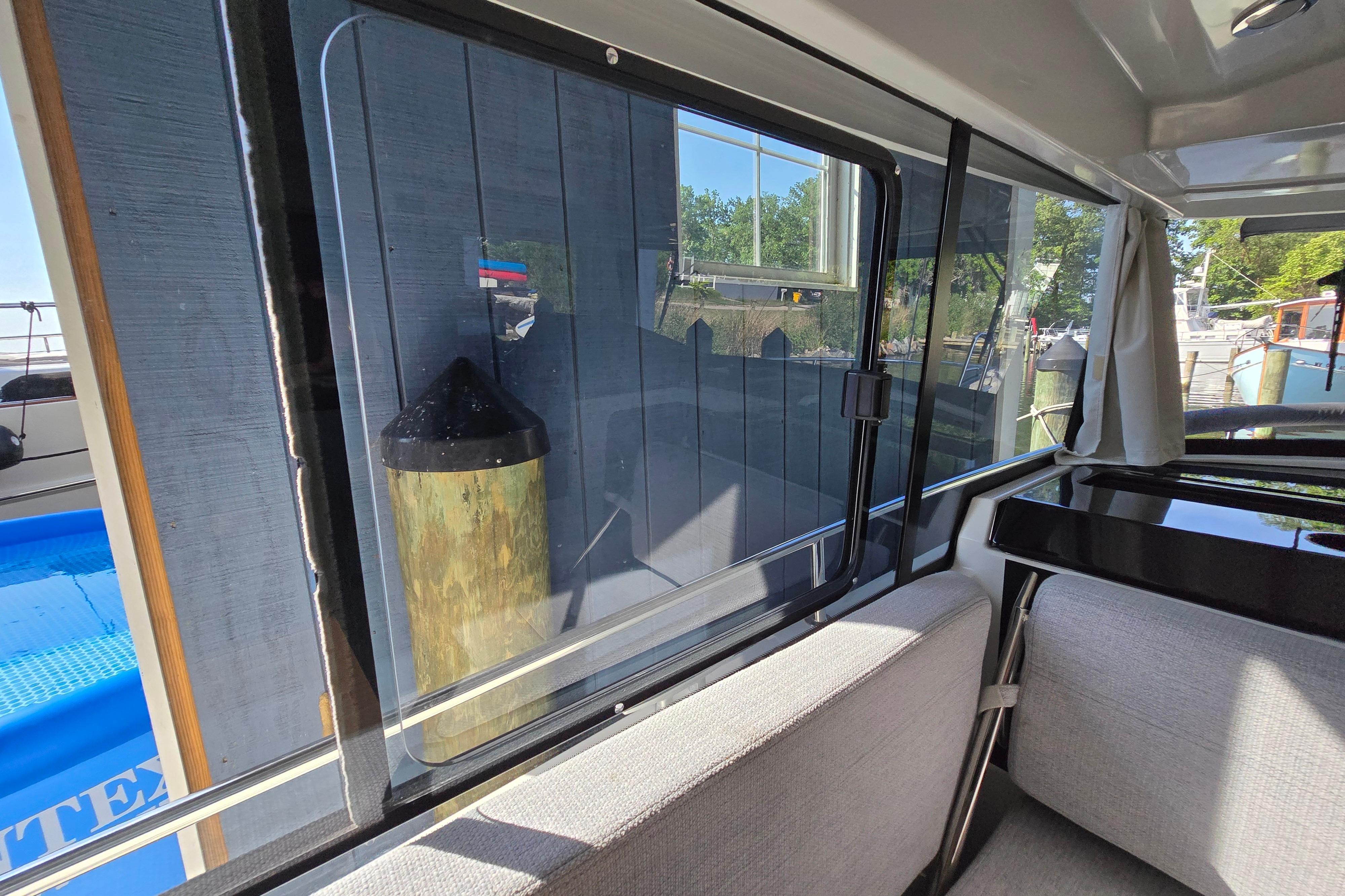 Interior view of a Jeanneau NC Sport 895 with gray upholstery and large windows.