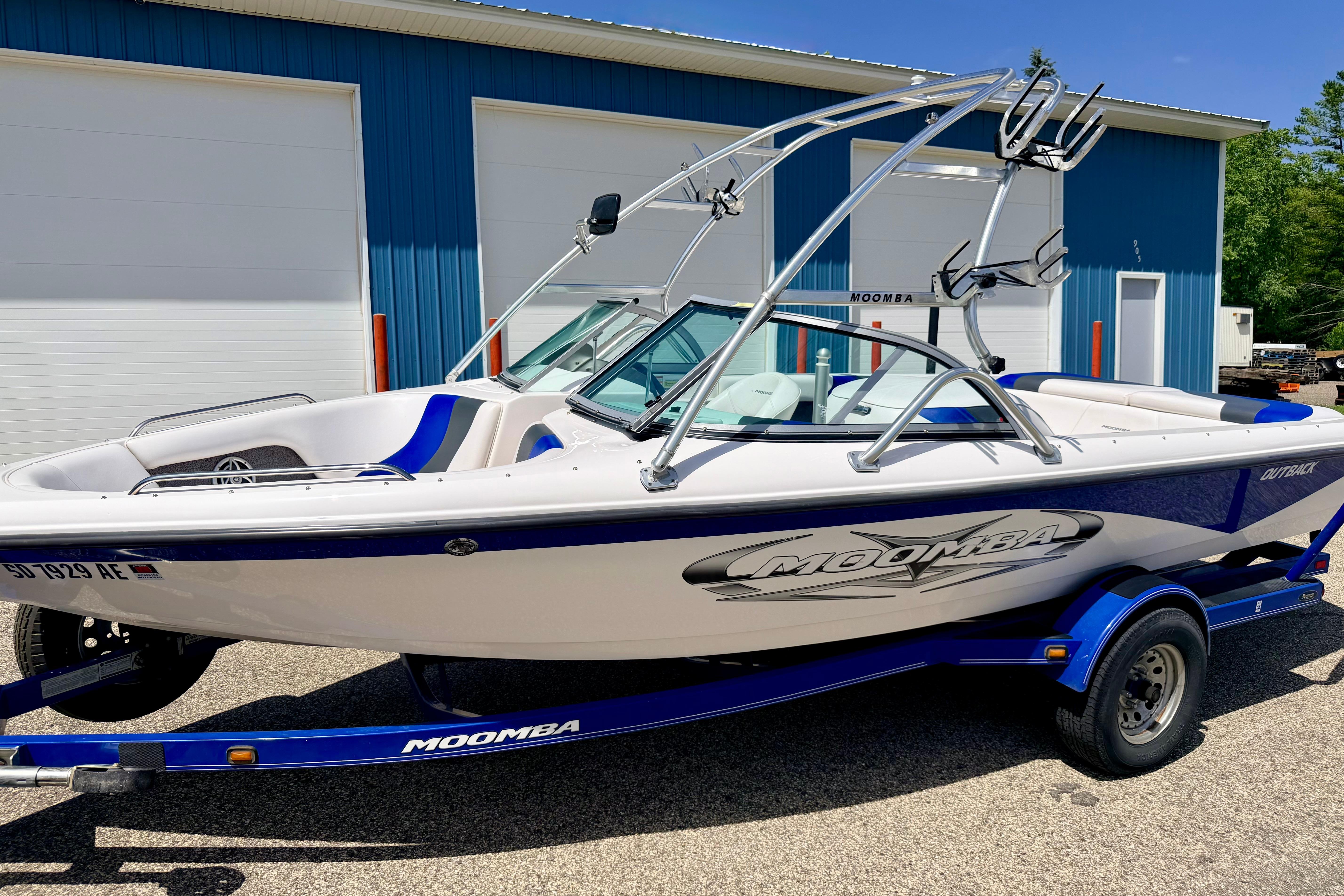2008 Moomba Outback V boat on trailer, parked near blue building.