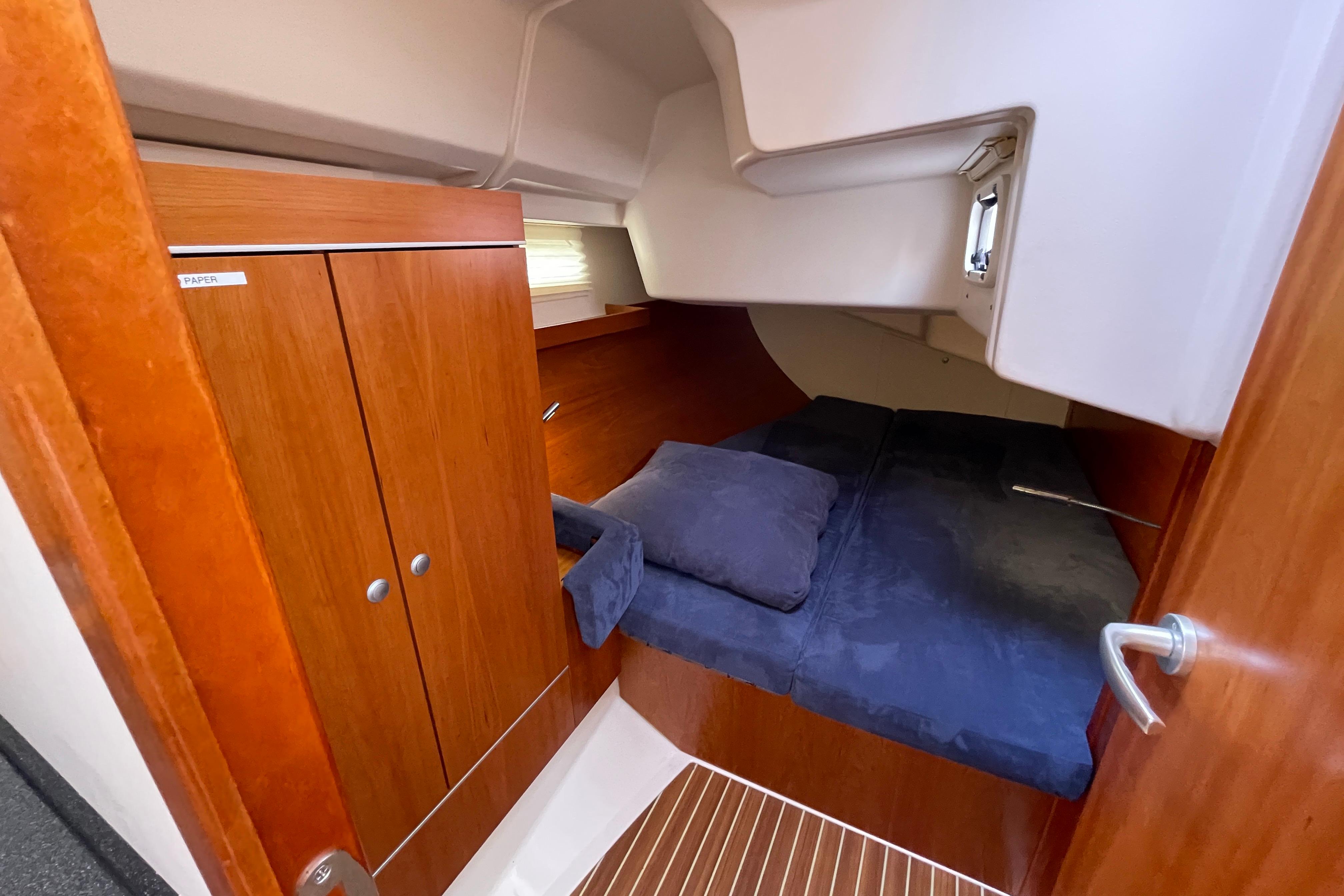 Cozy cabin interior of 2014 Hanse 415 yacht with wooden cabinetry and bed.