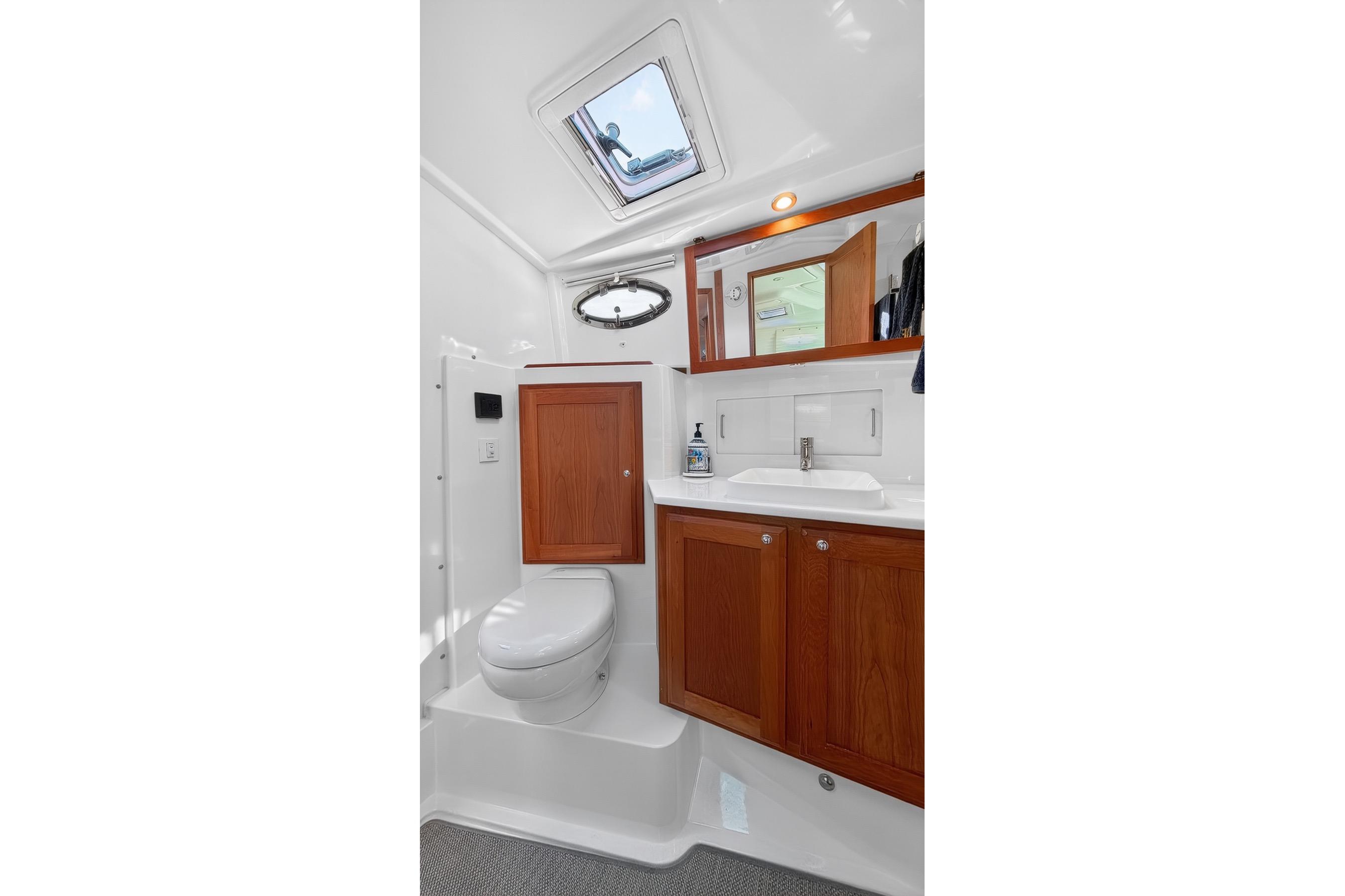 2024 Back Cove 39O yacht bathroom with wooden cabinets and skylight.
