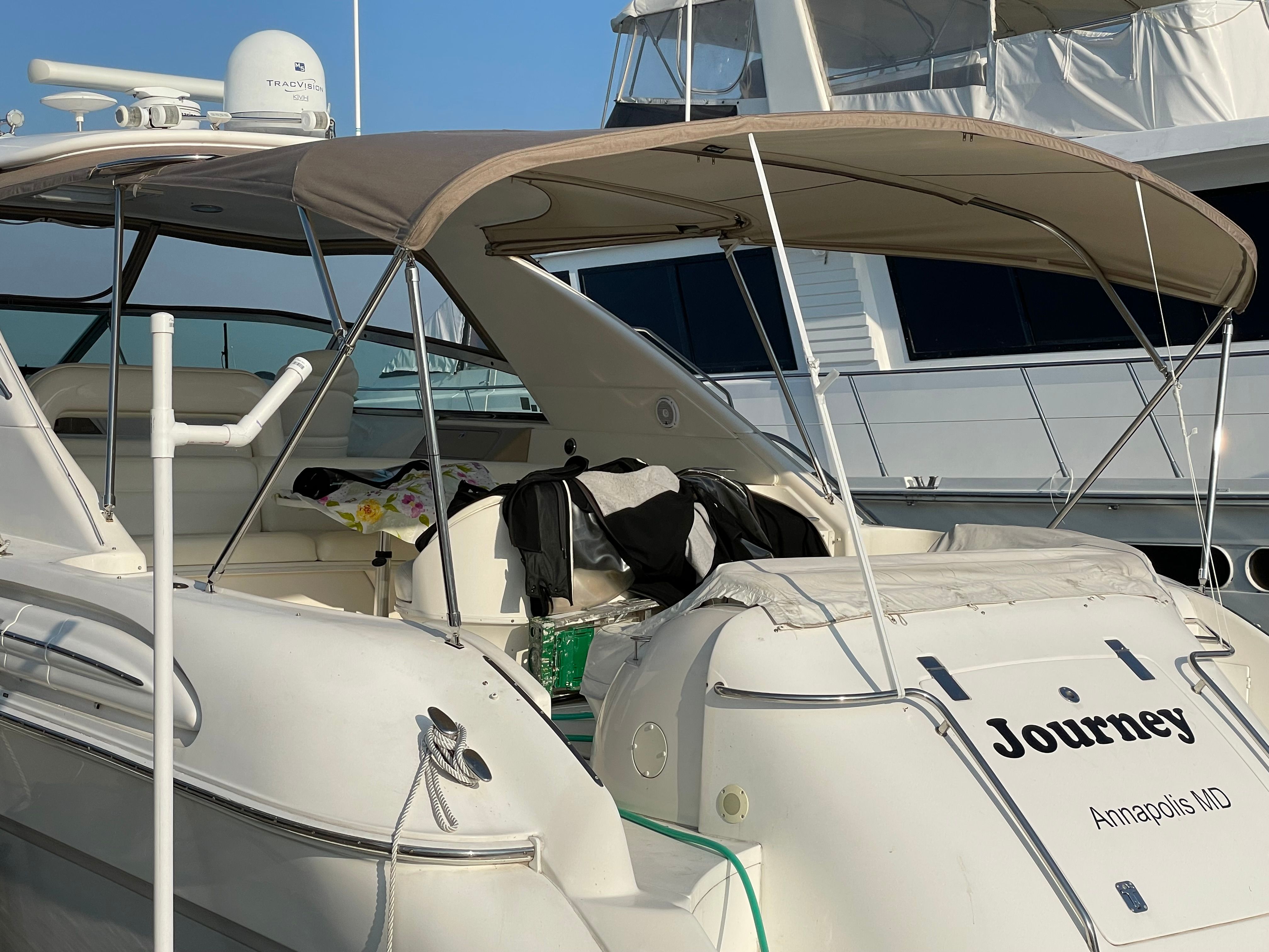 A 2003 Sea Ray S600 Sunsport docked at a marina. It features a beige sunshade and white exterior.