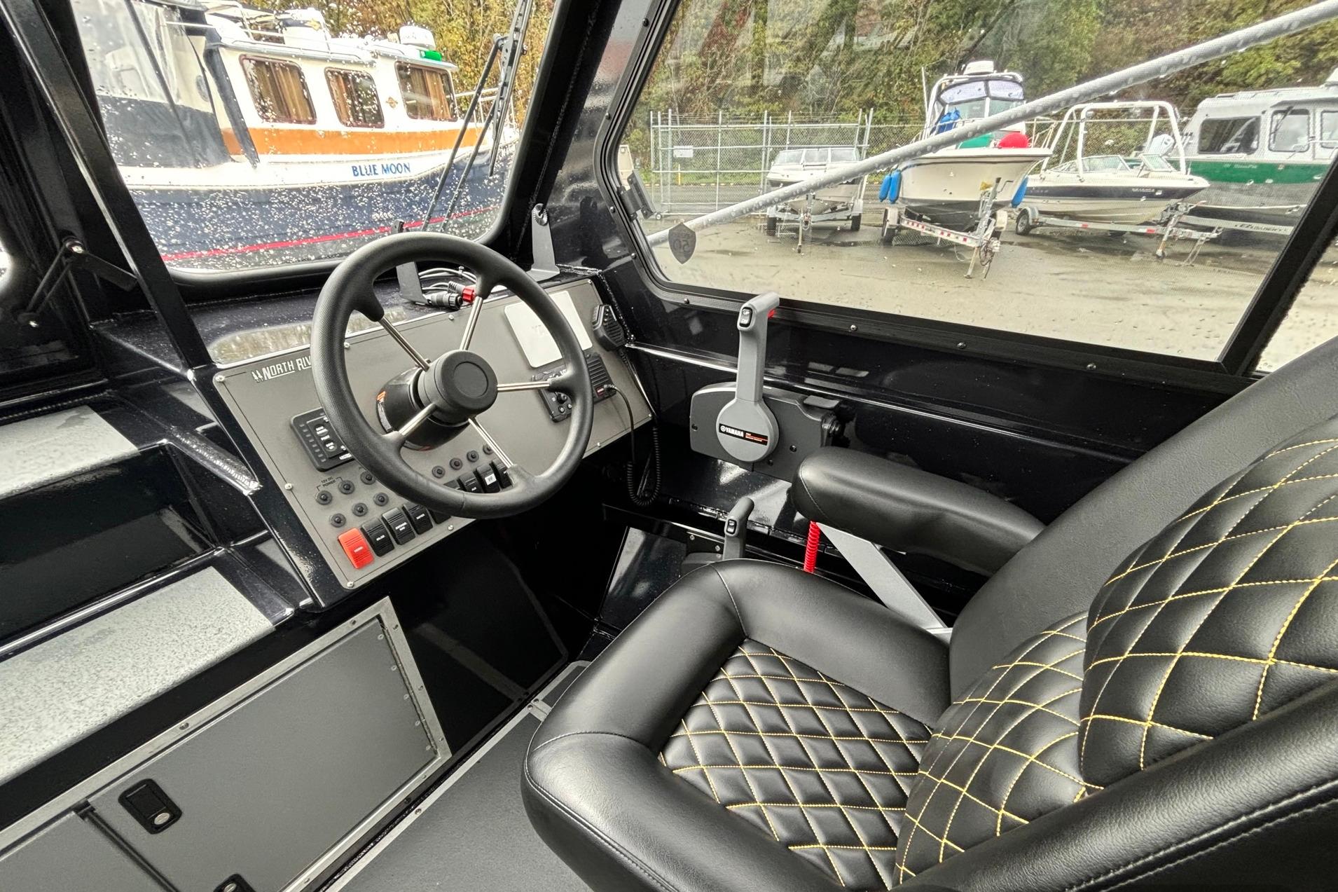 Interior of 2024 North River 21 Fastback boat with steering wheel and quilted seat.