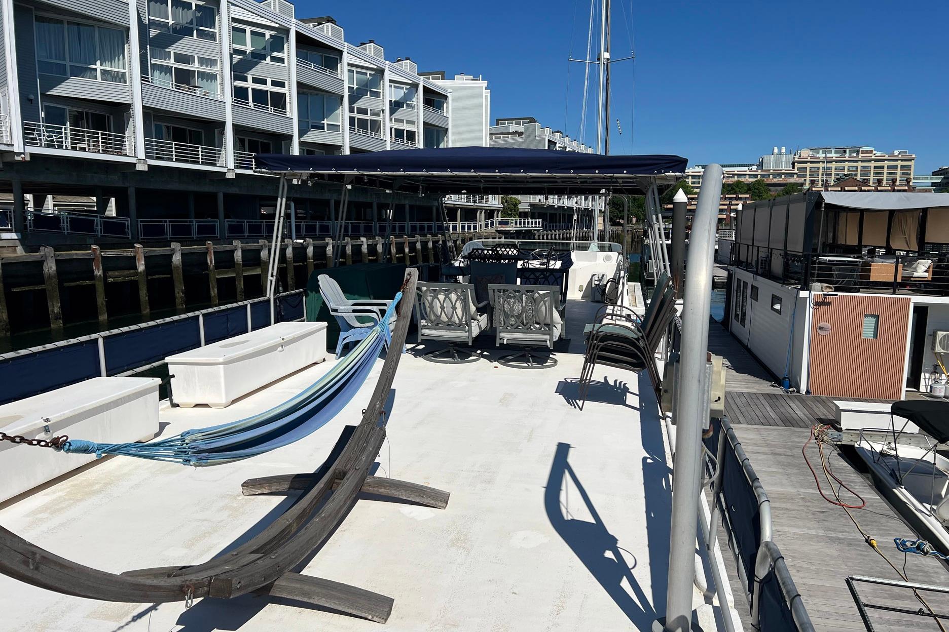 1993 Sumerset houseboat with spacious deck, hammock, and seating, docked near modern buildings.