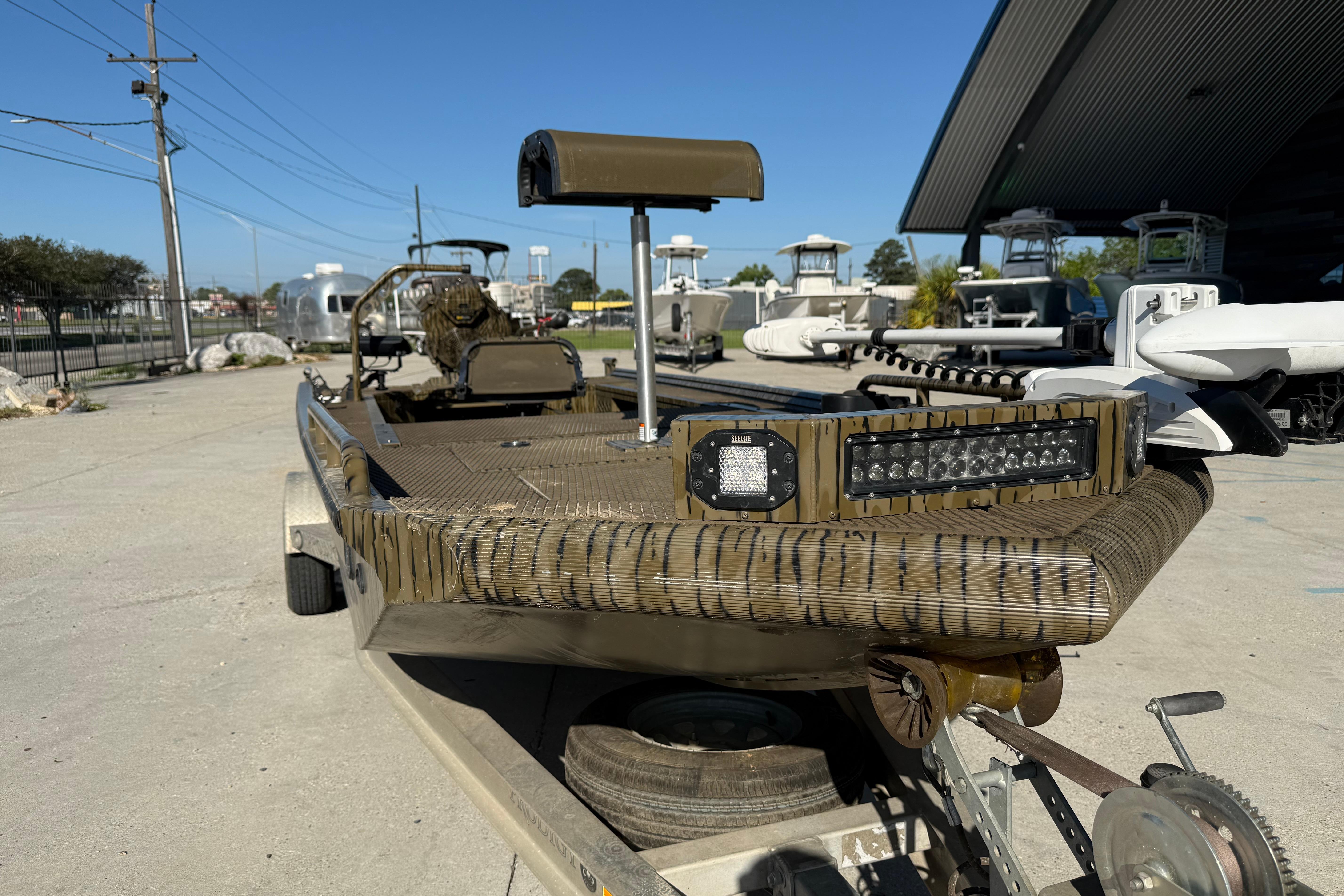 2022 Prodigy 1854 boat with camouflage design, parked on a trailer in a marina.