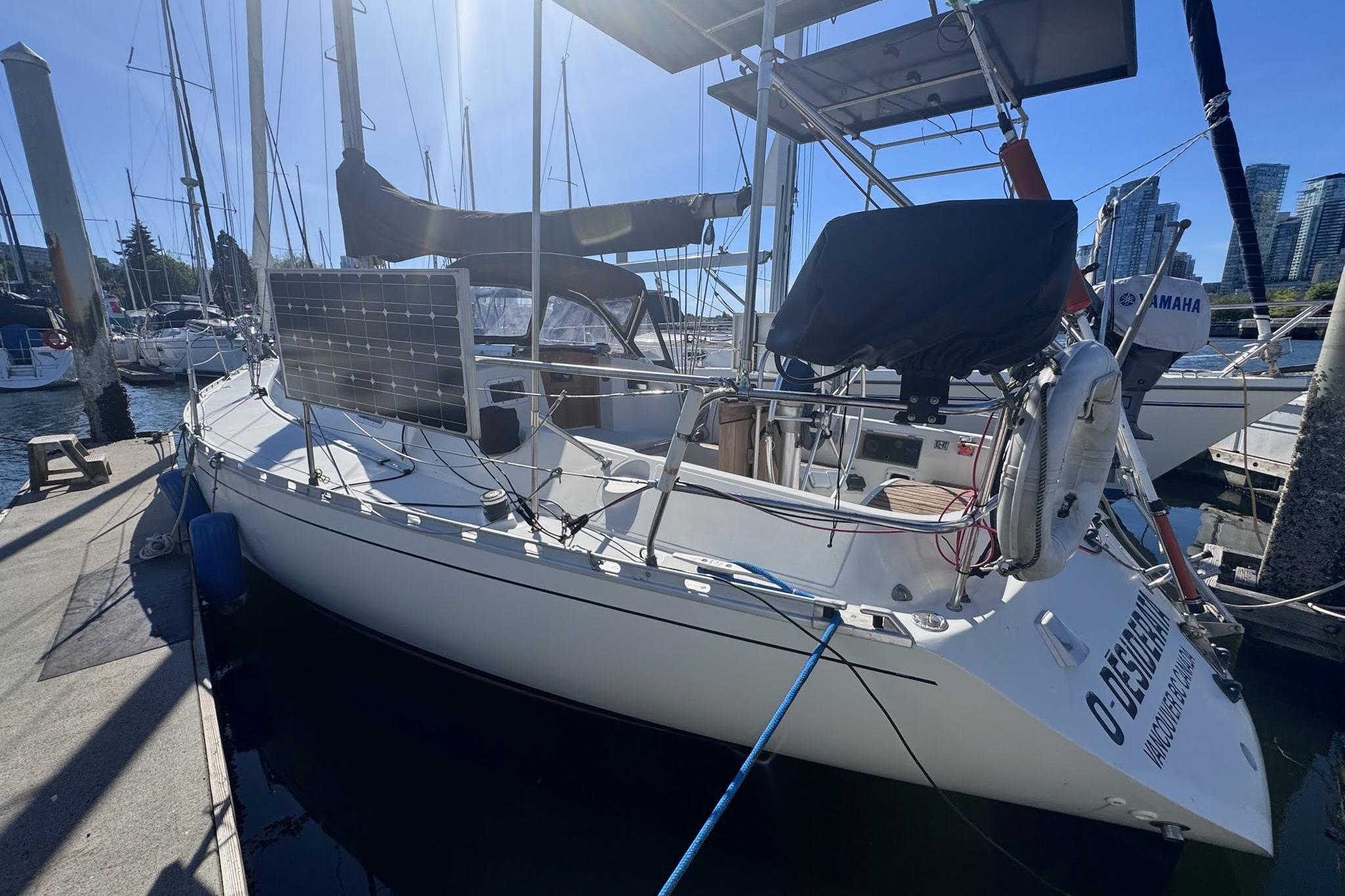 1985 Beneteau First 375 sailboat docked, featuring solar panels and marina backdrop.