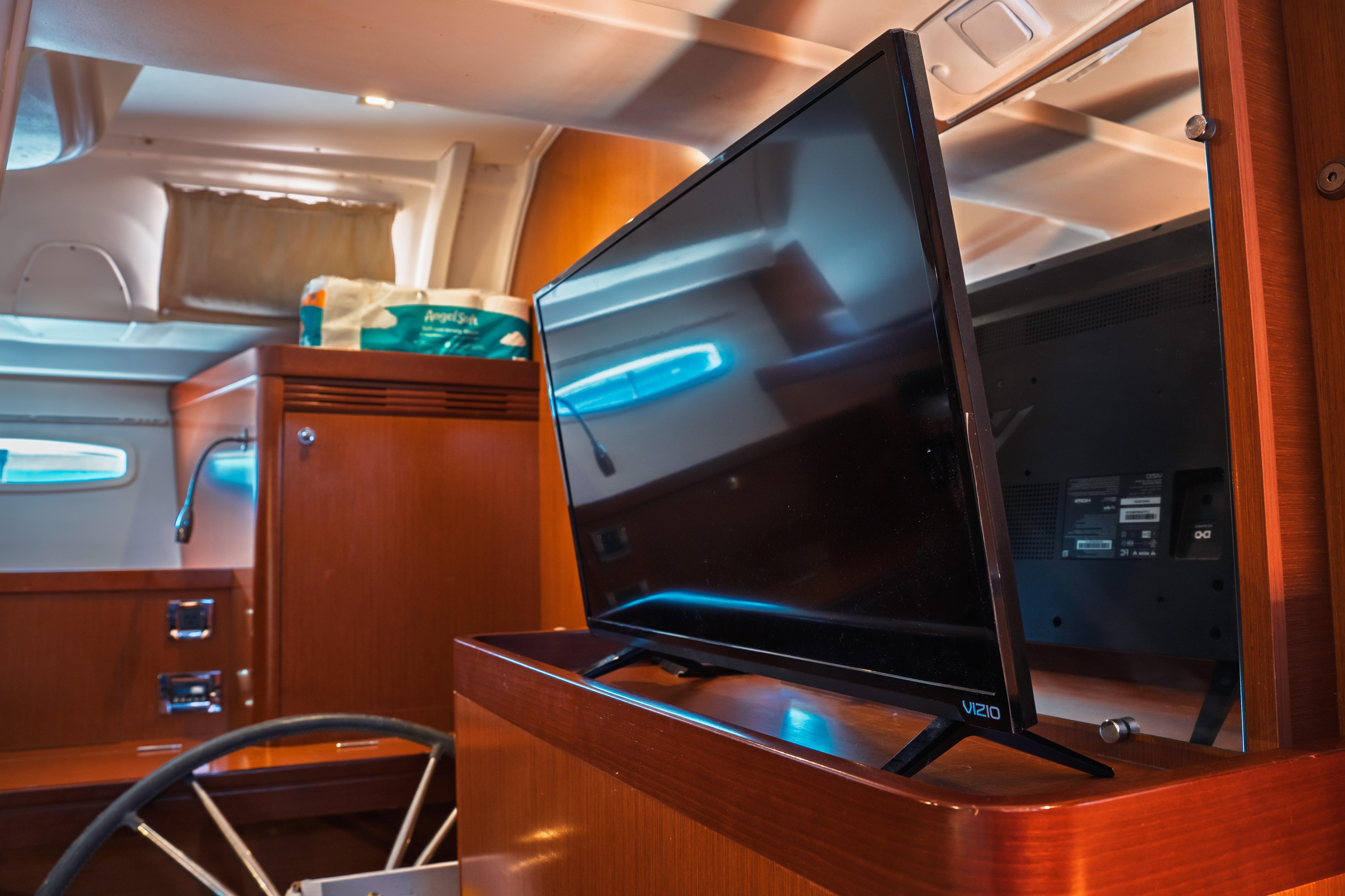 Interior of 2011 Beneteau Oceanis 50 yacht with TV and wooden cabinetry.